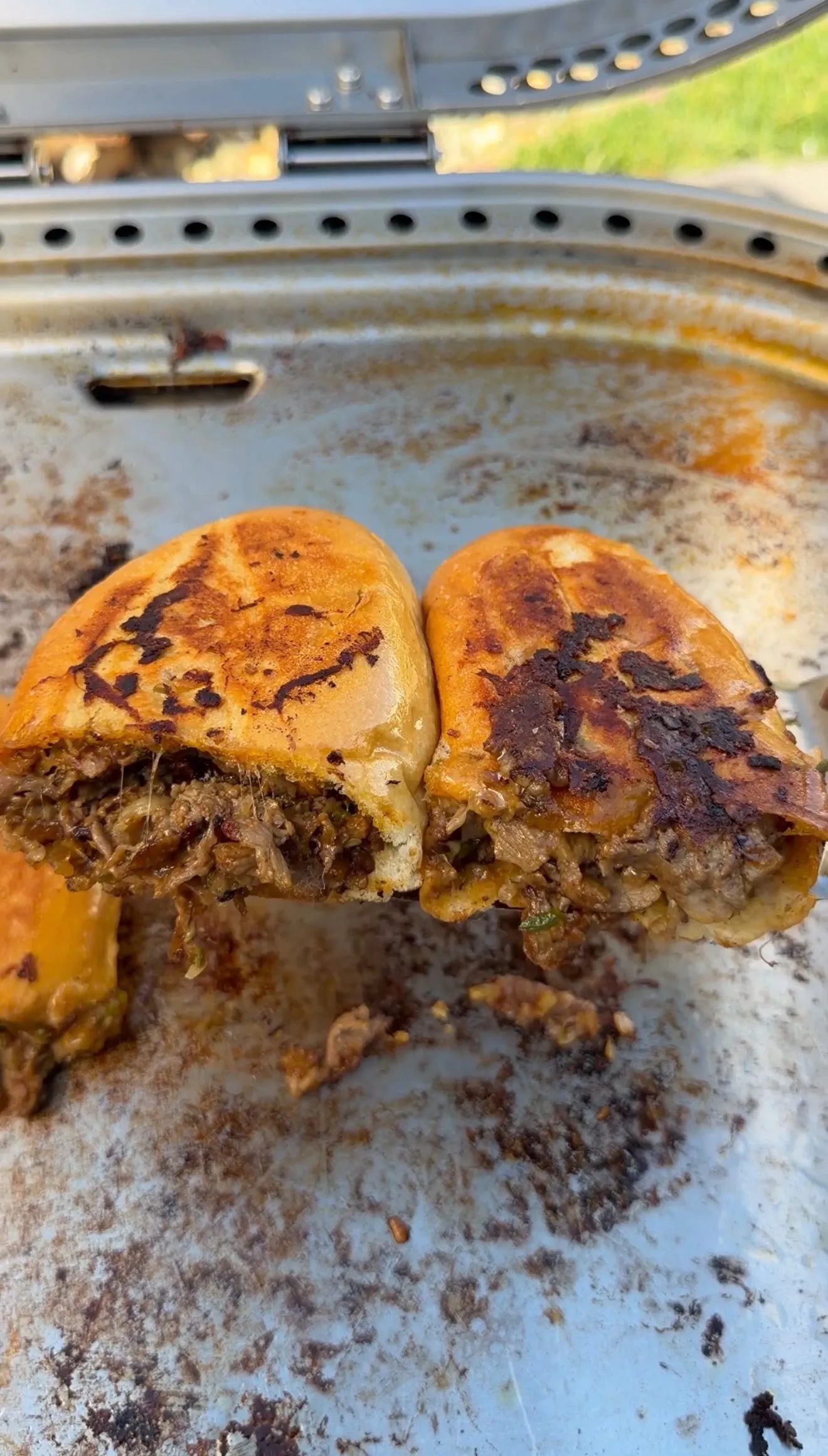 Halved cheesesteak stuffed bolillo bread with melted cheese and shredded beef, toasted on a griddle