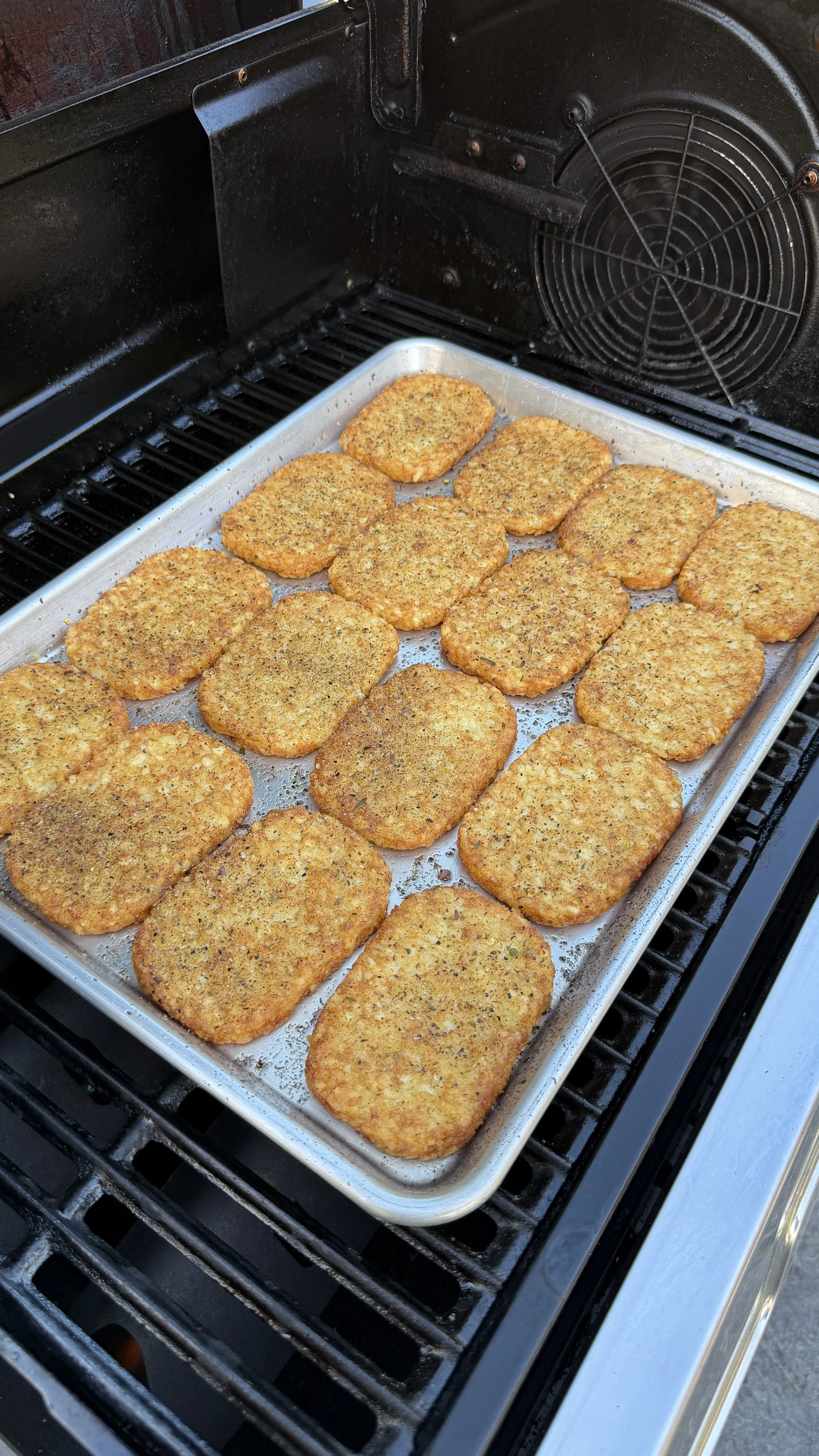 Golden crispy hash brown patties arranged on a baking sheet inside an open oven