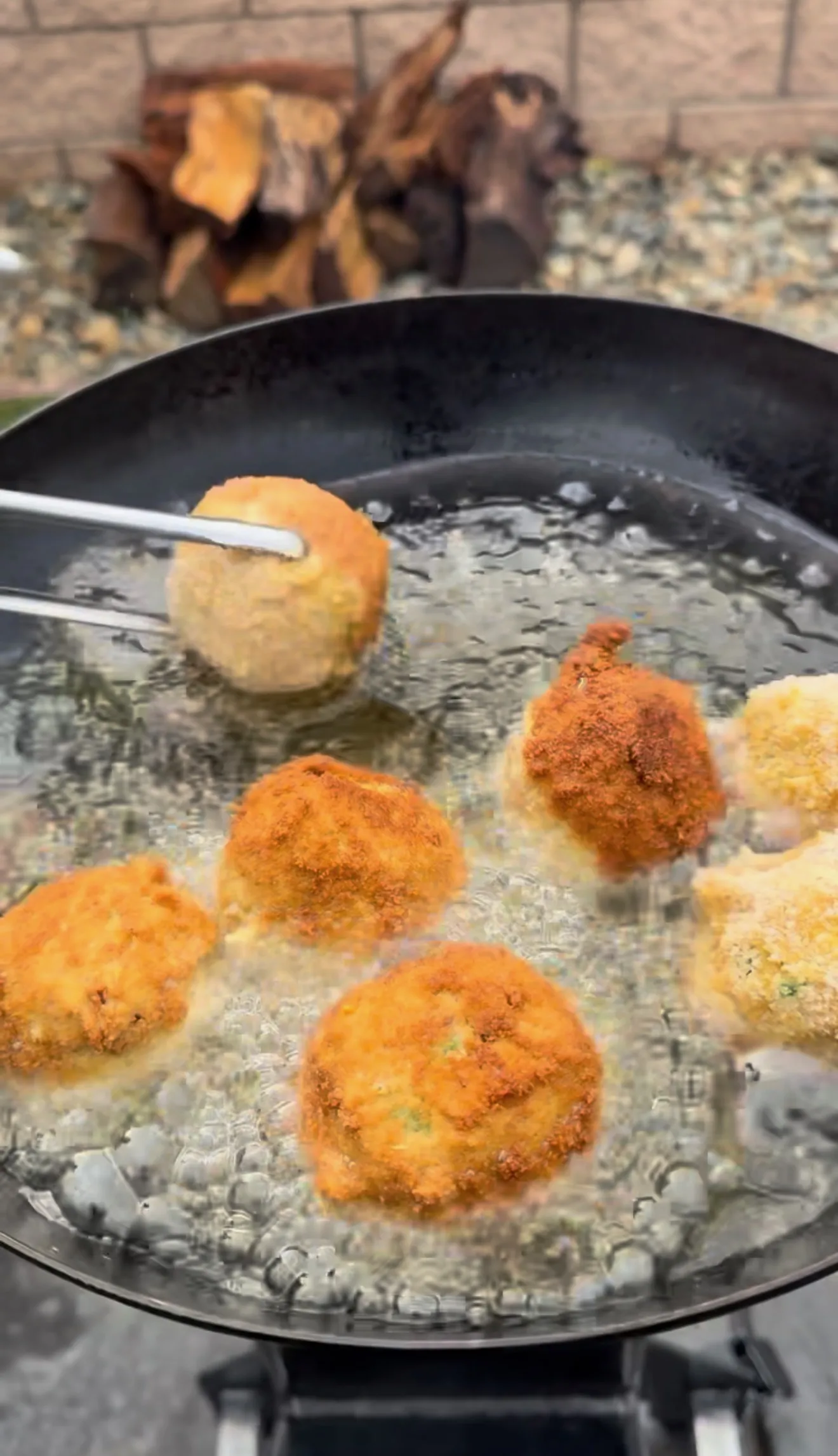 Golden-brown deep fried jalapeño popper bites bubbling in hot oil in a large black skillet