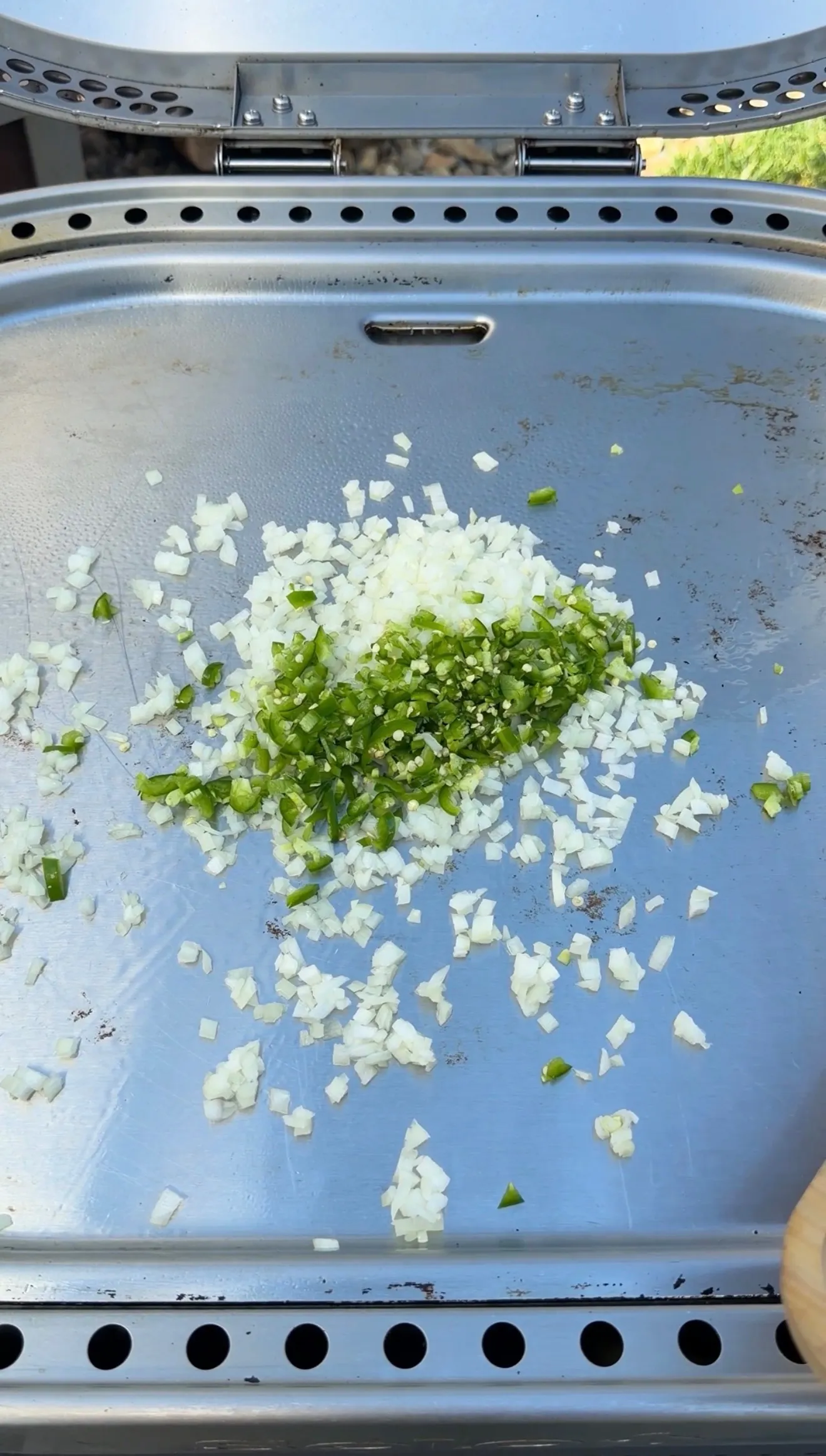 Finely diced white onions and chopped jalapeños on a flat top griddle for cheesesteak stuffed bolillo bread