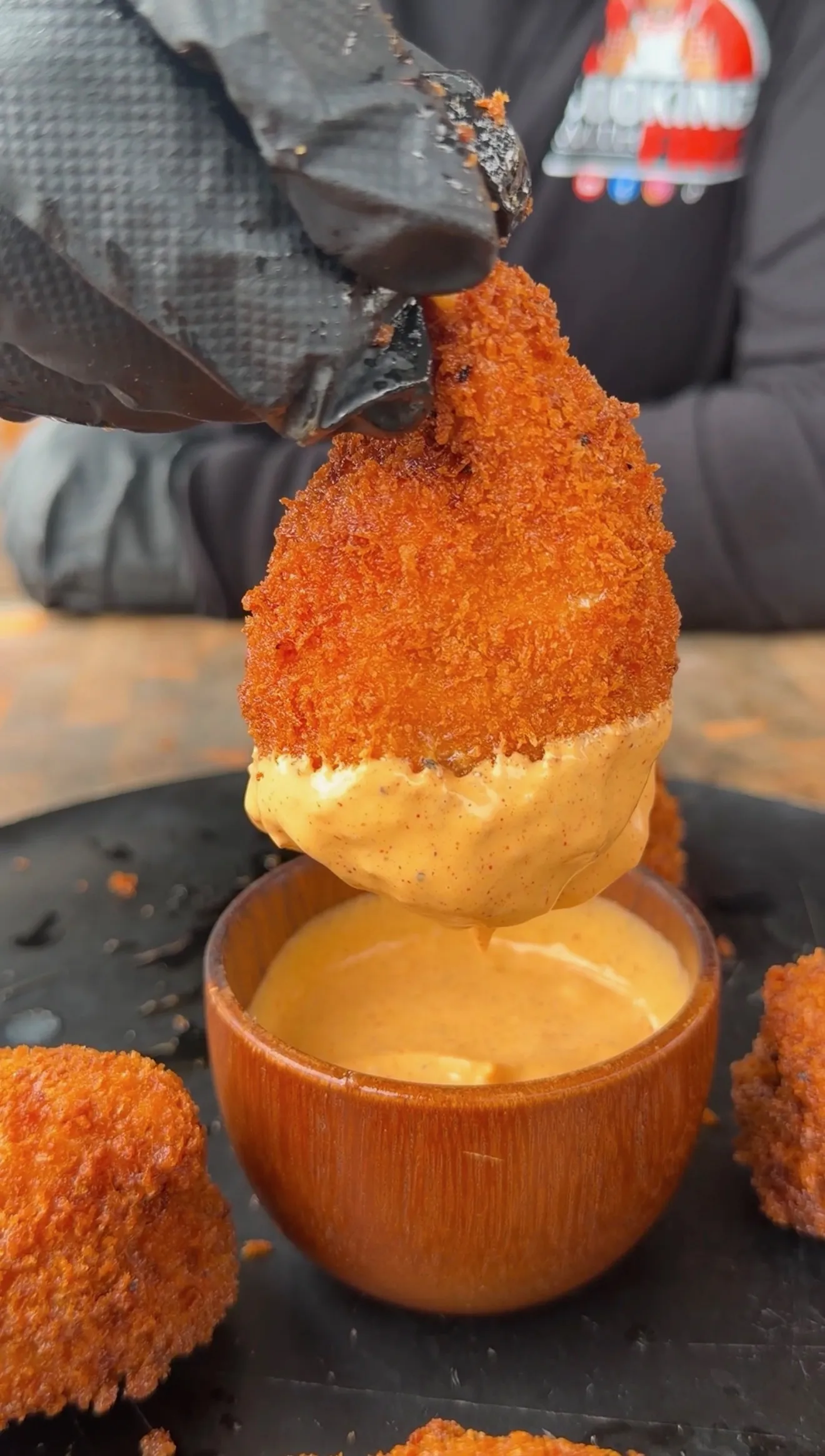 Crispy breaded jalapeño popper stuffed shrimp being dipped into creamy spicy aioli sauce