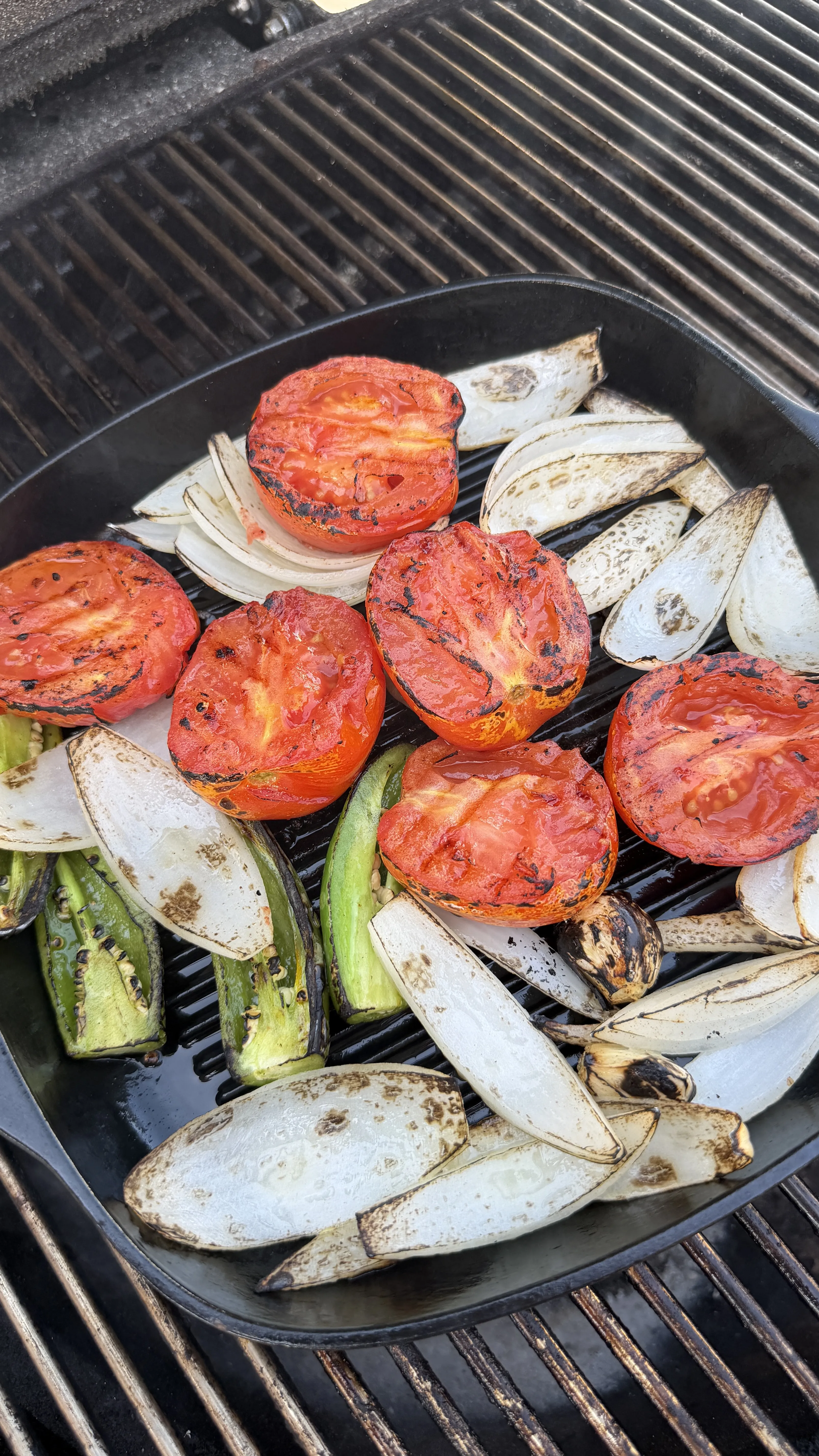 Grilled tomatoes, onions, and peppers in cast iron skillet on barbecue grill for skirt steak tacos