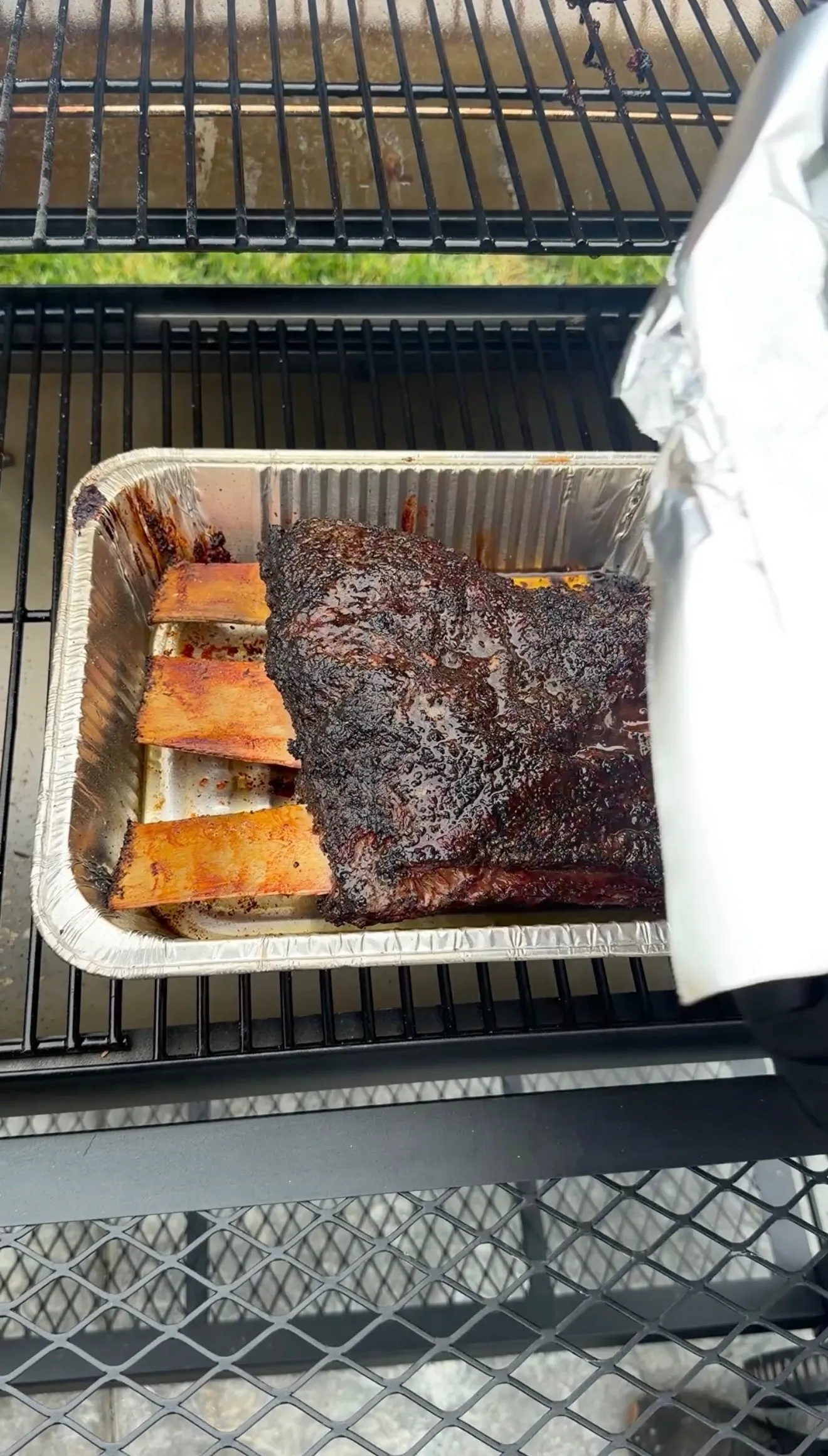 Hickory smoked beef plate ribs with dark bark in an aluminum pan on a pellet smoker grill