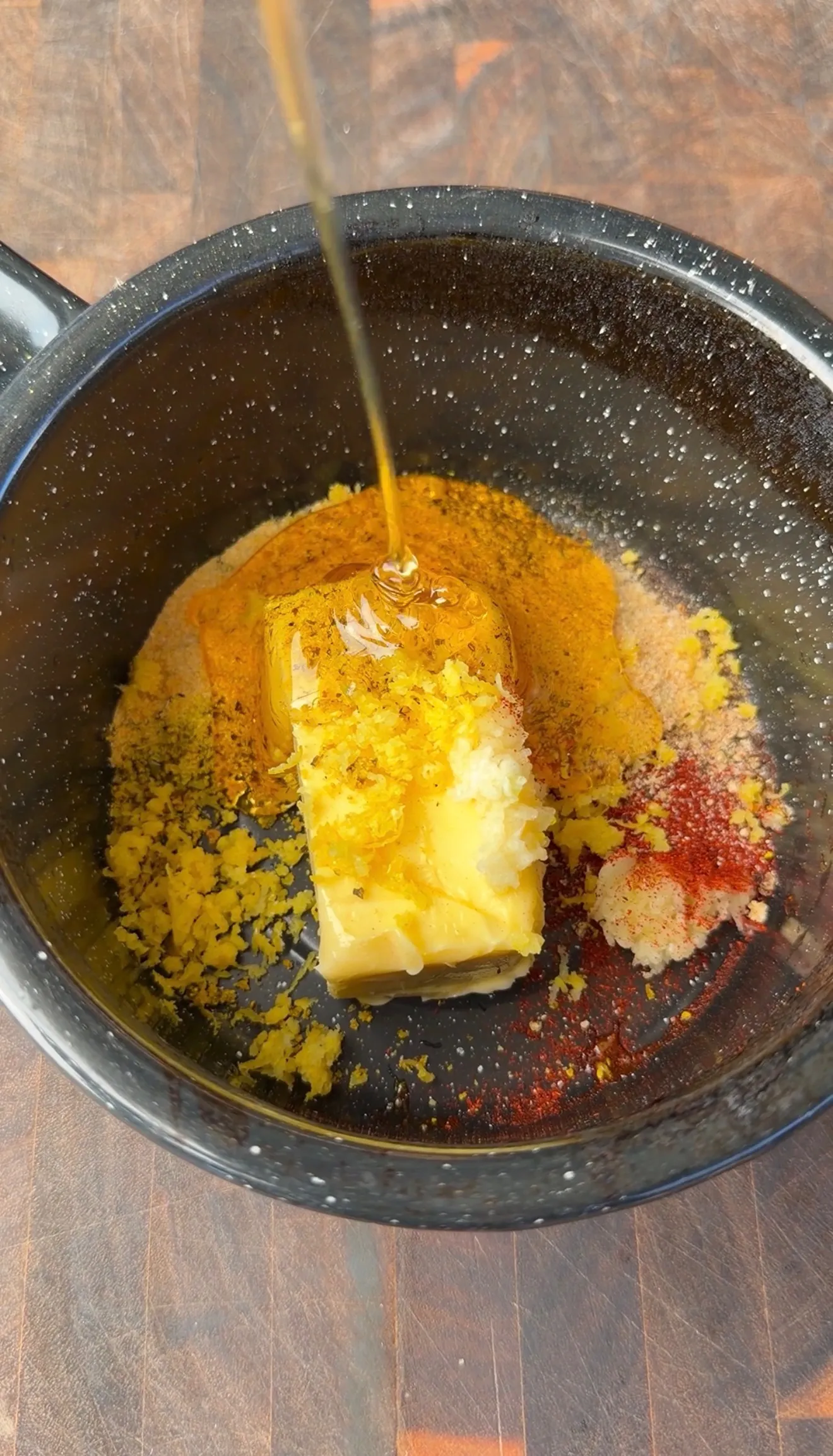 Butter, honey drizzle, lemon zest, and spices in a dark saucepan for wing sauce