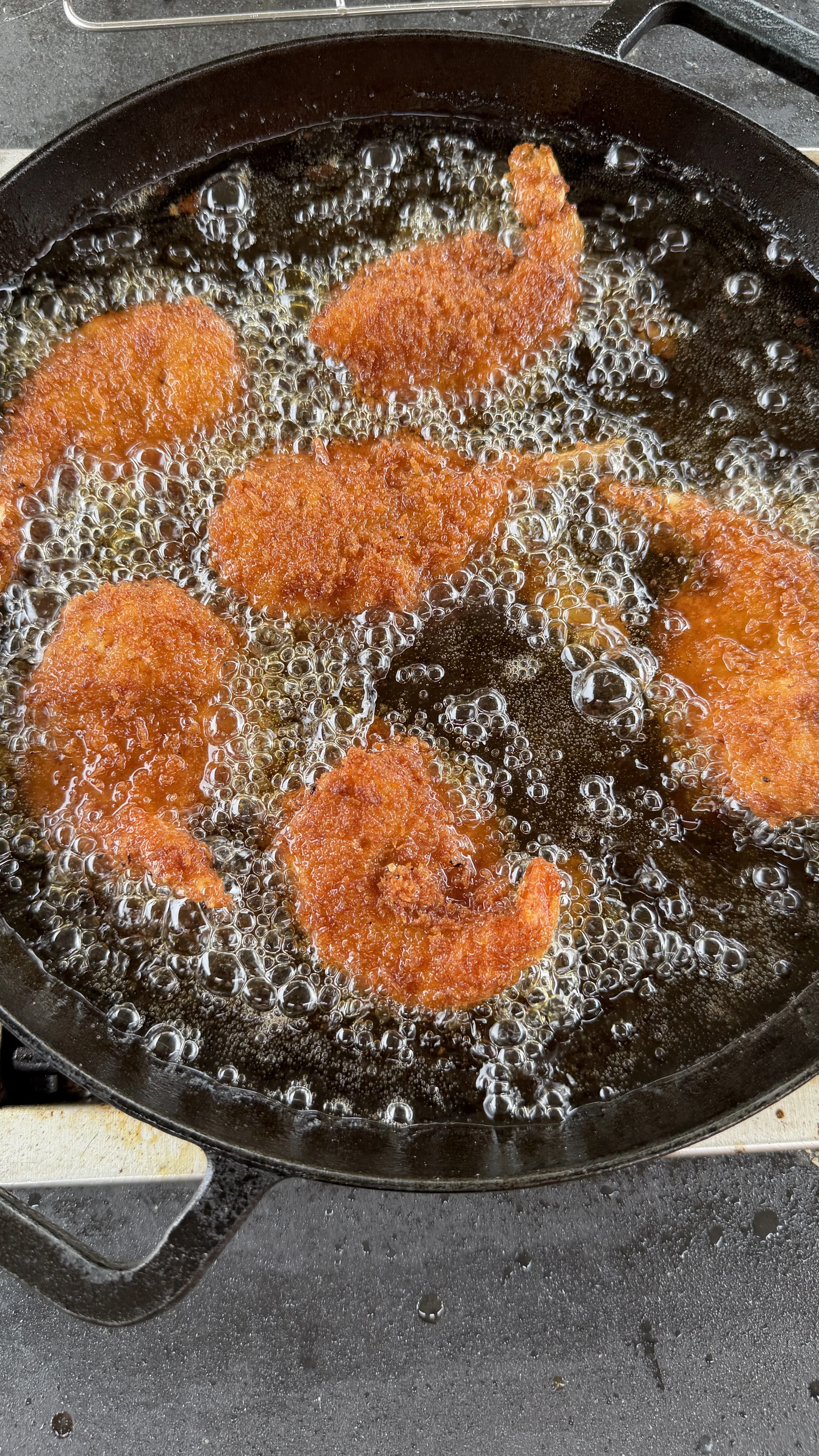 Breaded jalapeño popper stuffed shrimp sizzling in hot oil in a cast iron skillet