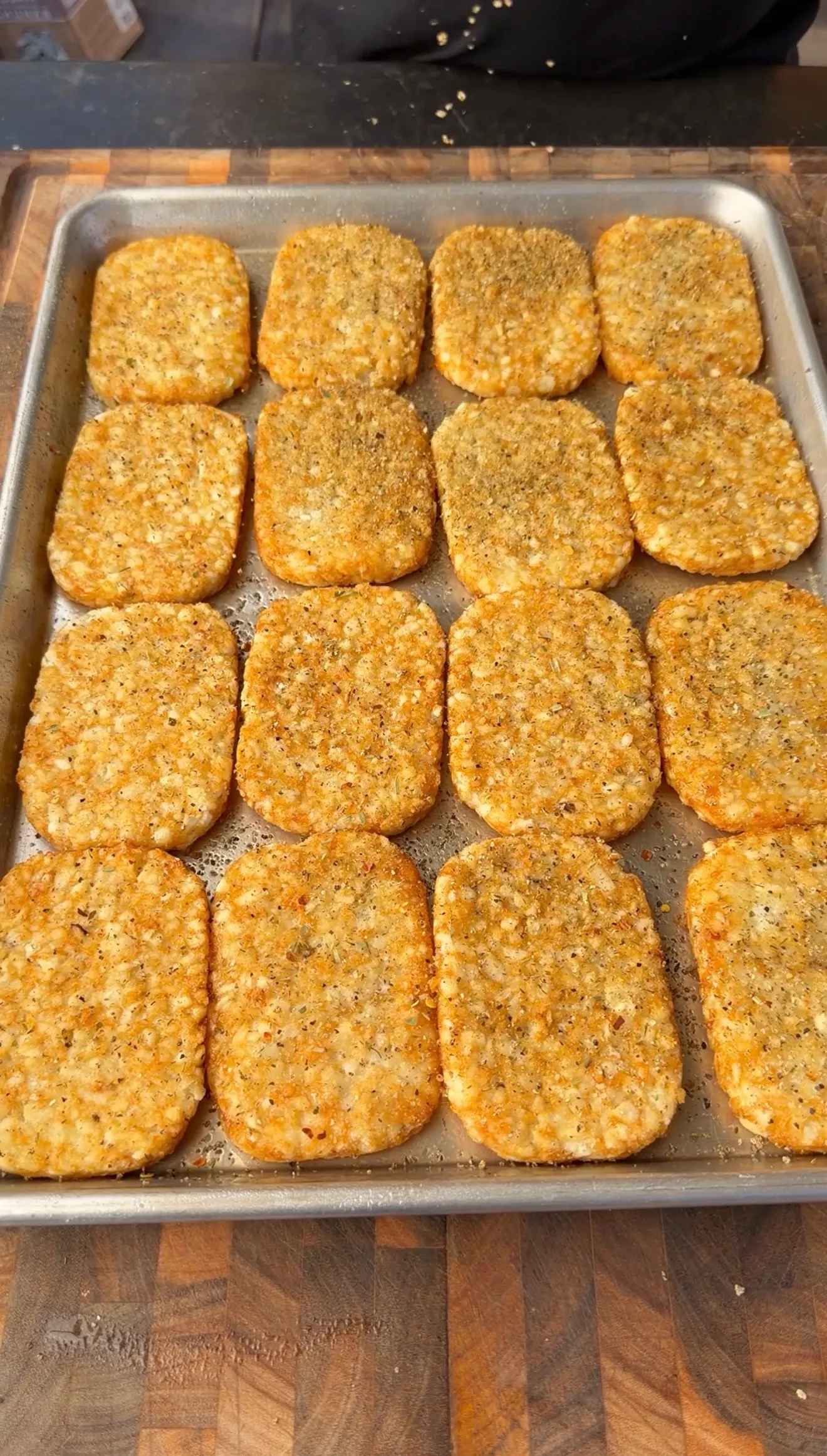 Golden loaded crispy hash browns arranged on a baking sheet, seasoned and ready to bake