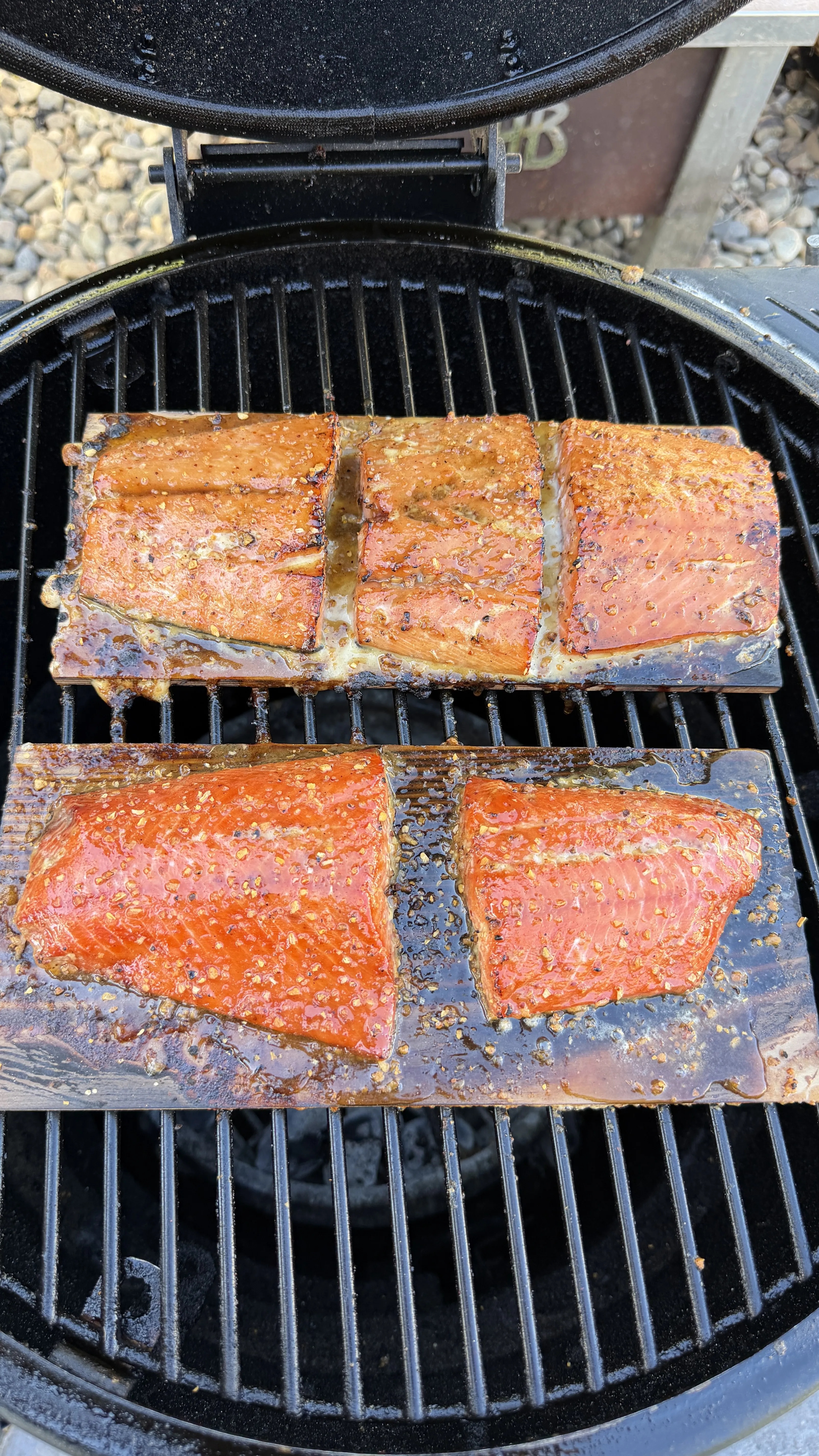 Glazed cedar plank salmon fillets with caramelized maple bourbon glaze cooking on a grill