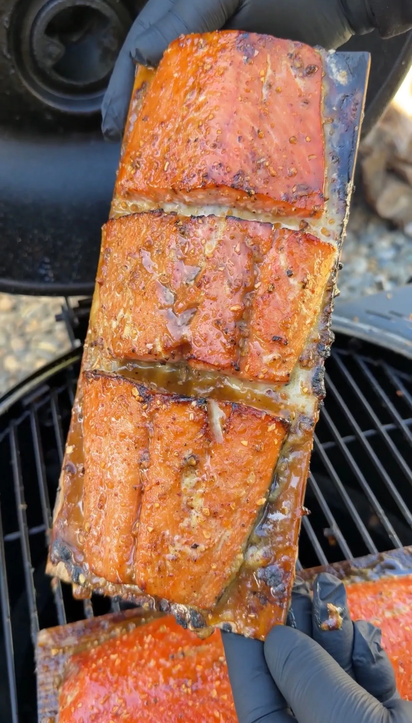 Glazed cedar plank smoked salmon with a caramelized maple bourbon crust held over a charcoal grill
