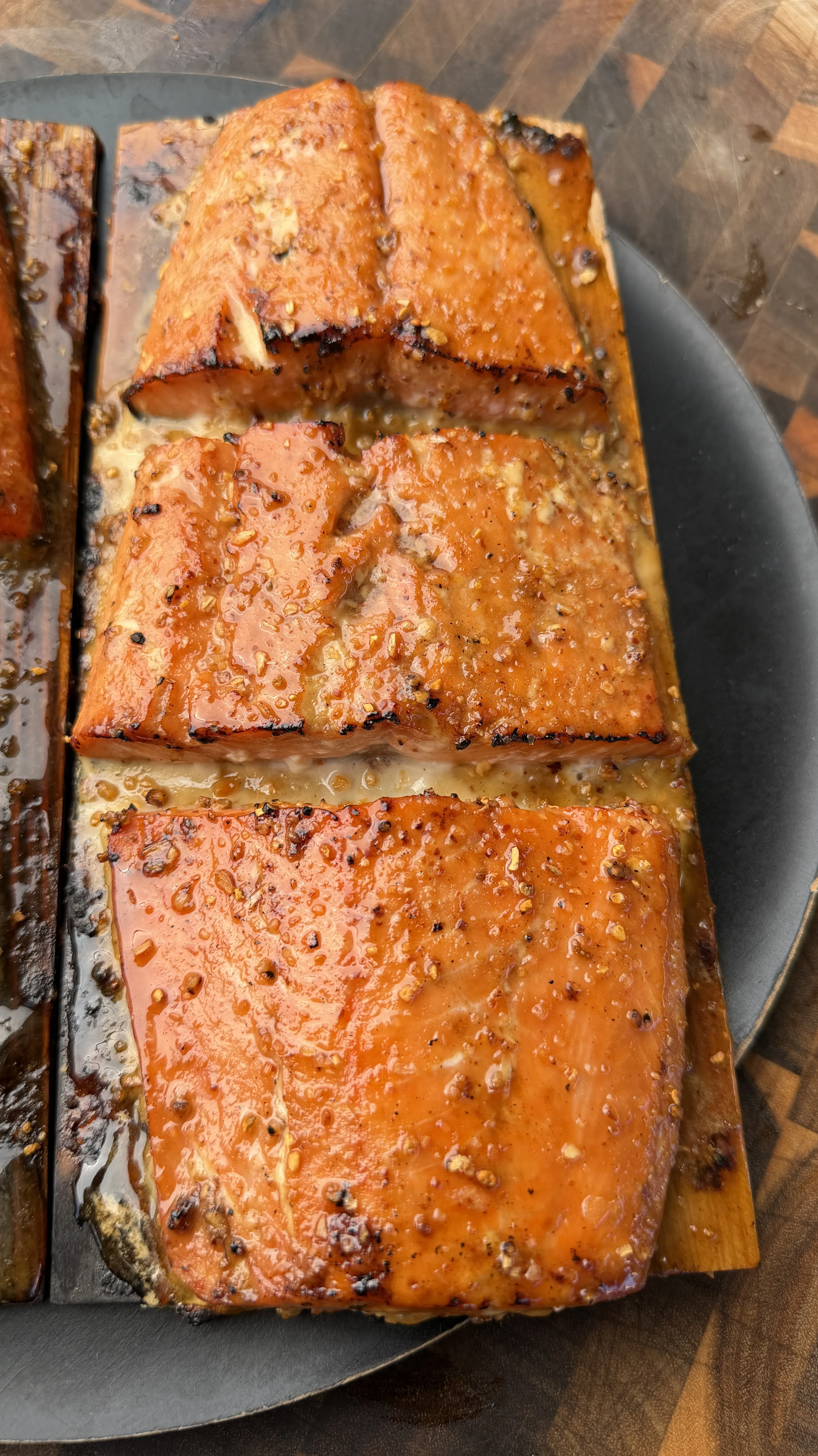 Glazed maple bourbon cedar plank smoked salmon fillets with caramelized crust on a dark serving platter