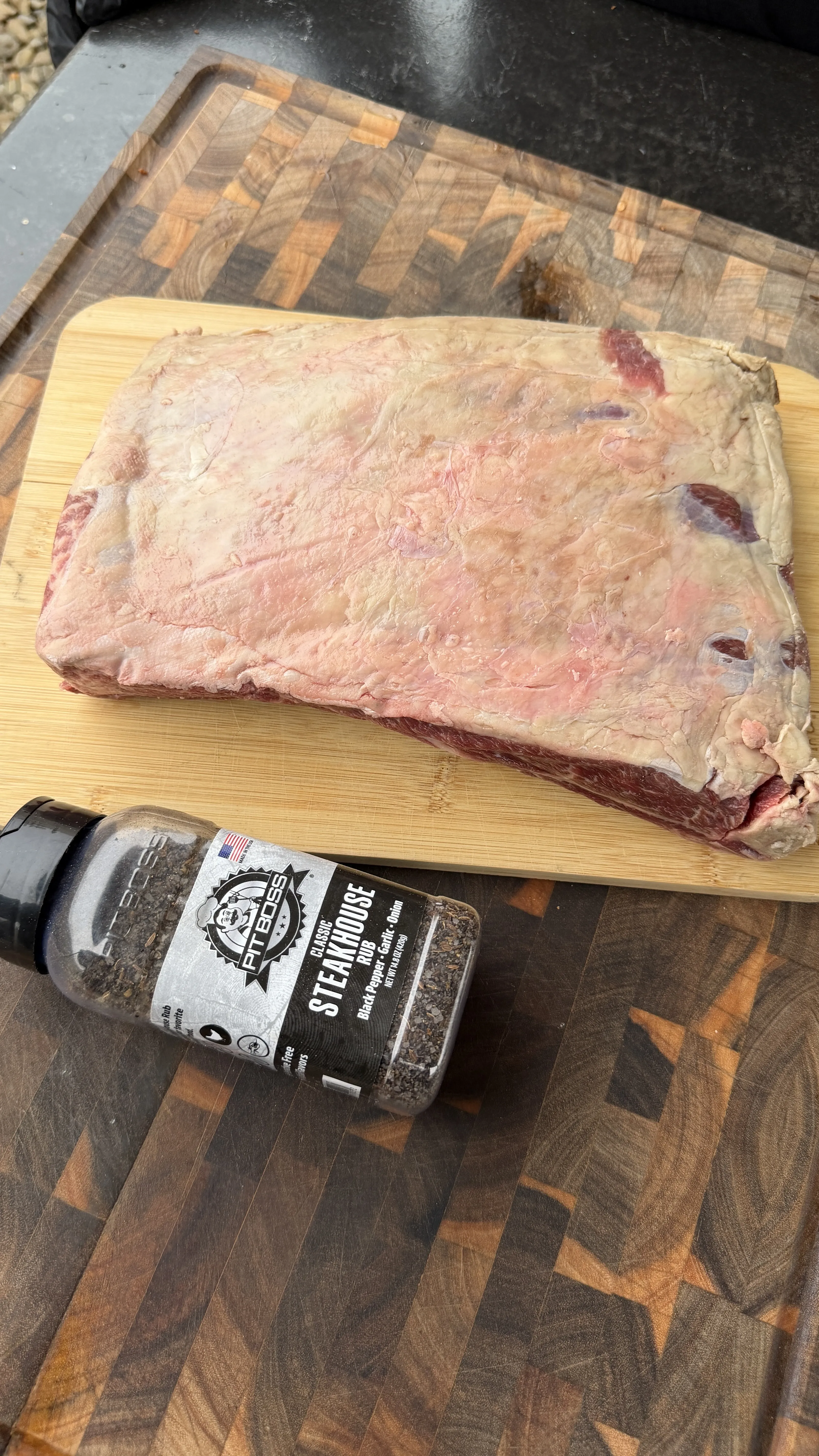 Raw beef plate ribs on a bamboo cutting board with a steakhouse-style rub seasoning