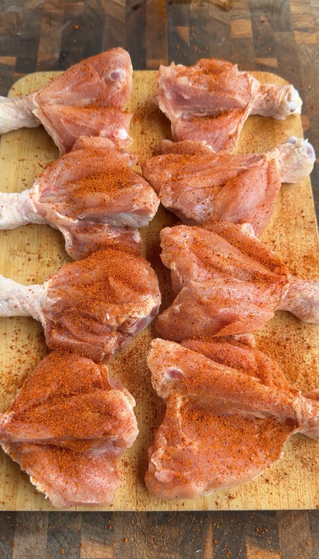 Raw chicken drumsticks generously coated with chili lime seasoning on a wooden cutting board