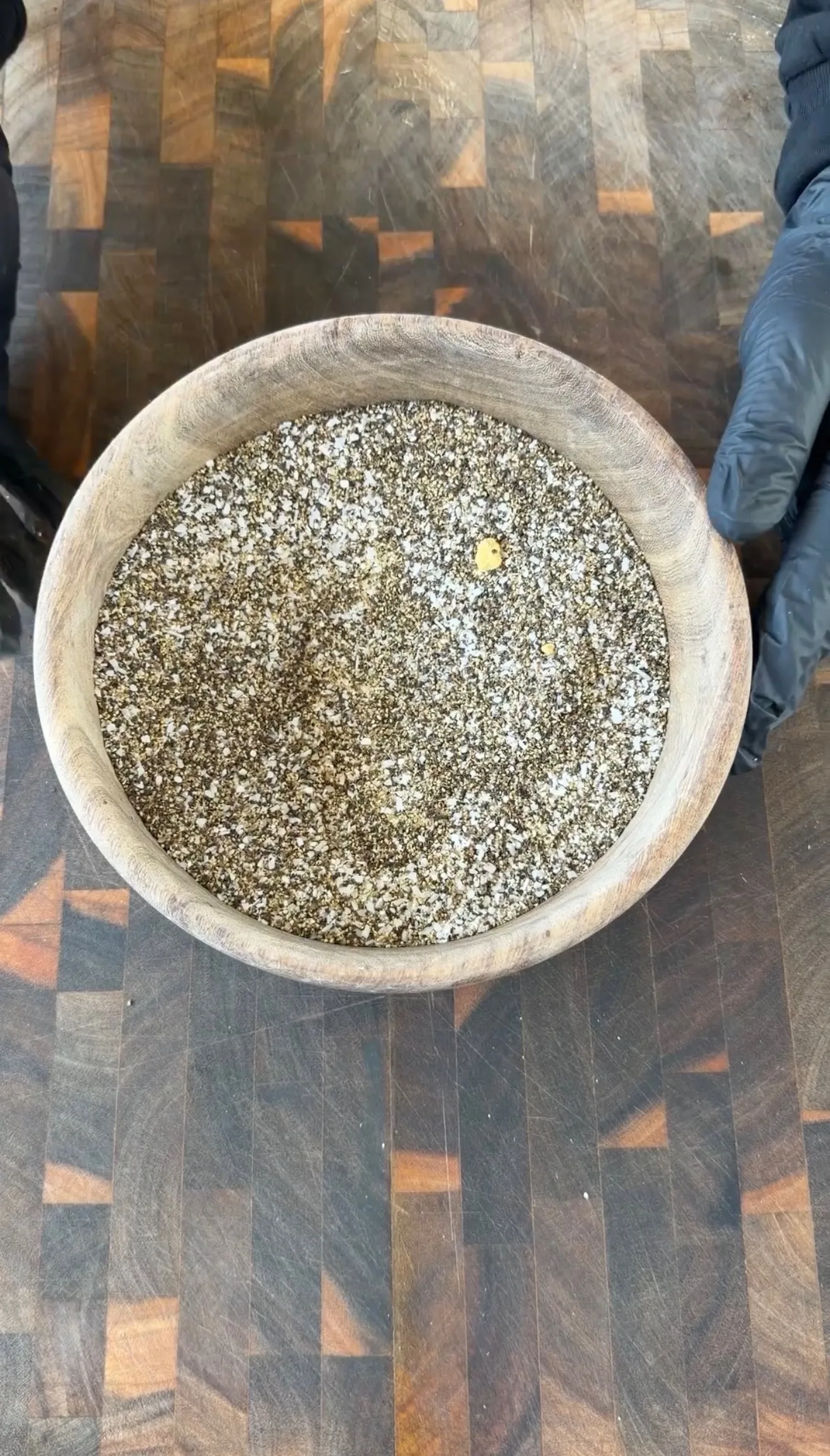Coarse salt and black pepper dry rub for smoked brisket in a rustic wooden bowl on a butcher block