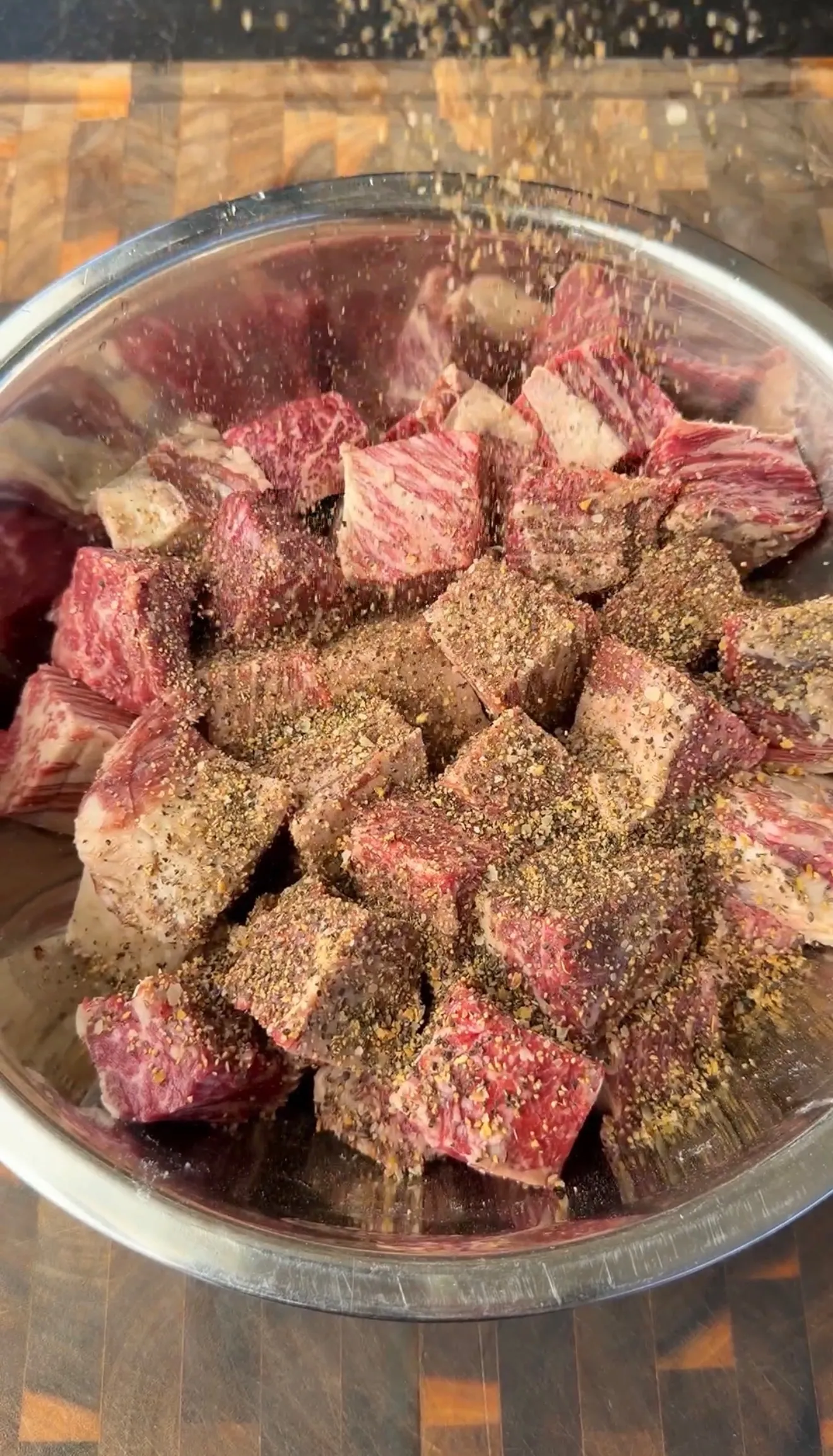 Raw beef rib burnt ends cubes seasoned with molasses coffee rub in a clear glass bowl before smoking