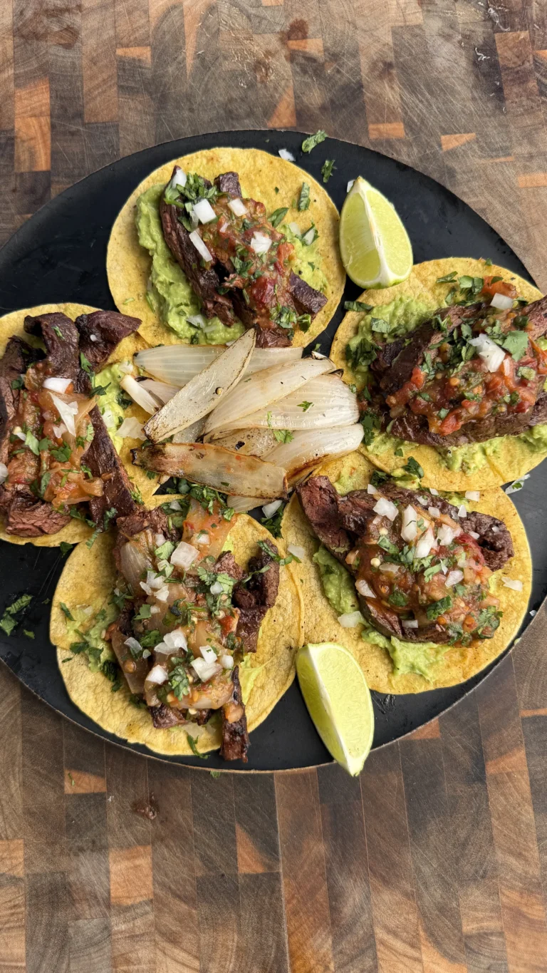 Skirt steak tacos with chipotle salsa, guacamole, onions and cilantro on corn tortillas with lime wedges