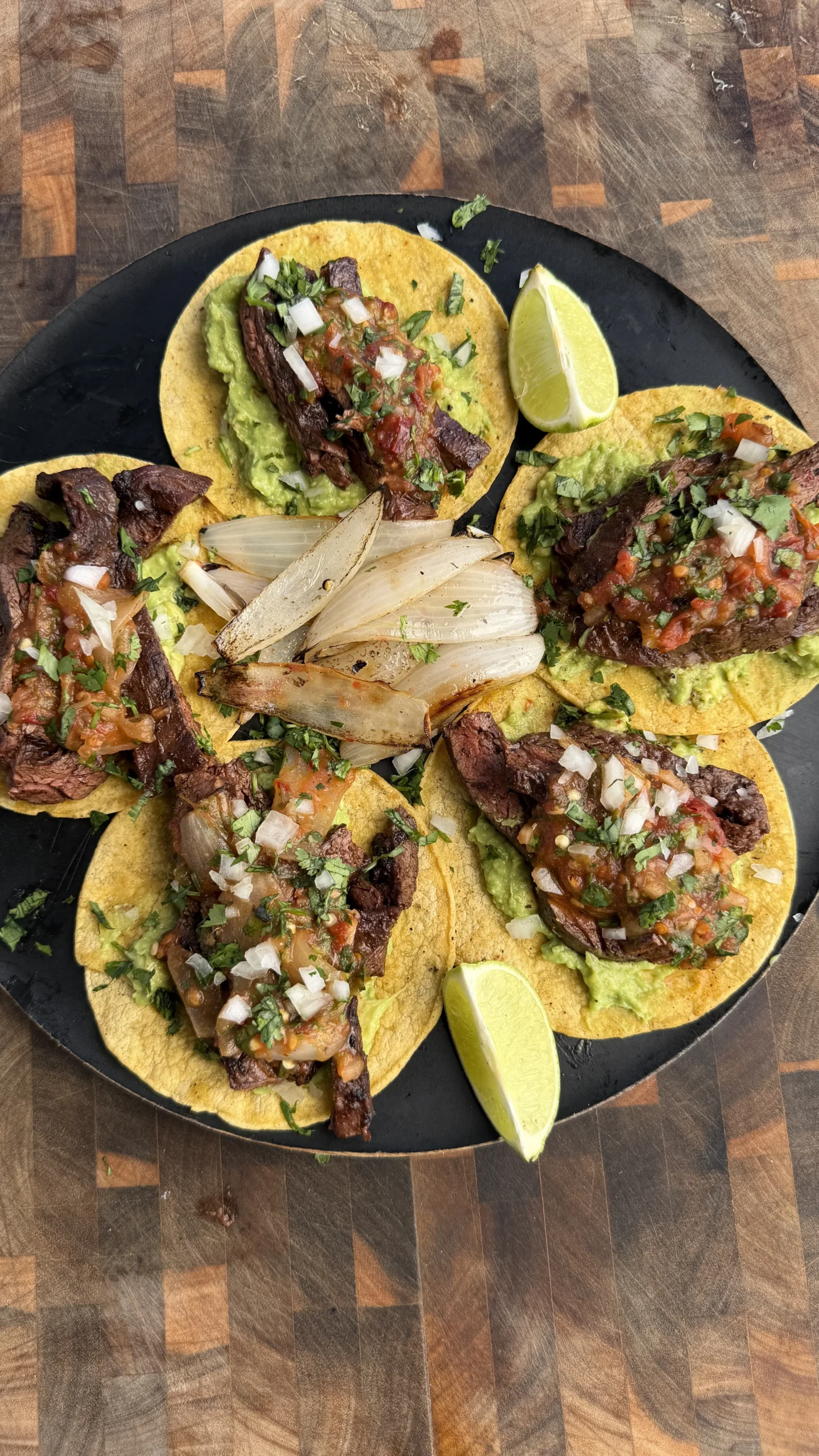 Skirt steak tacos with chipotle salsa, guacamole, onions and cilantro on corn tortillas with lime wedges