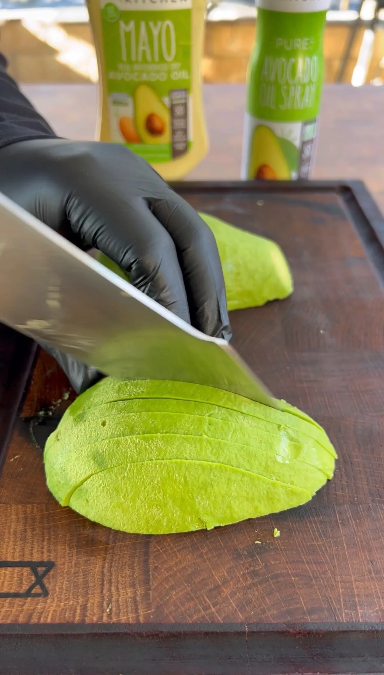 Fresh ripe avocado sliced on wooden cutting board with knife for avocado BLT sandwich preparation