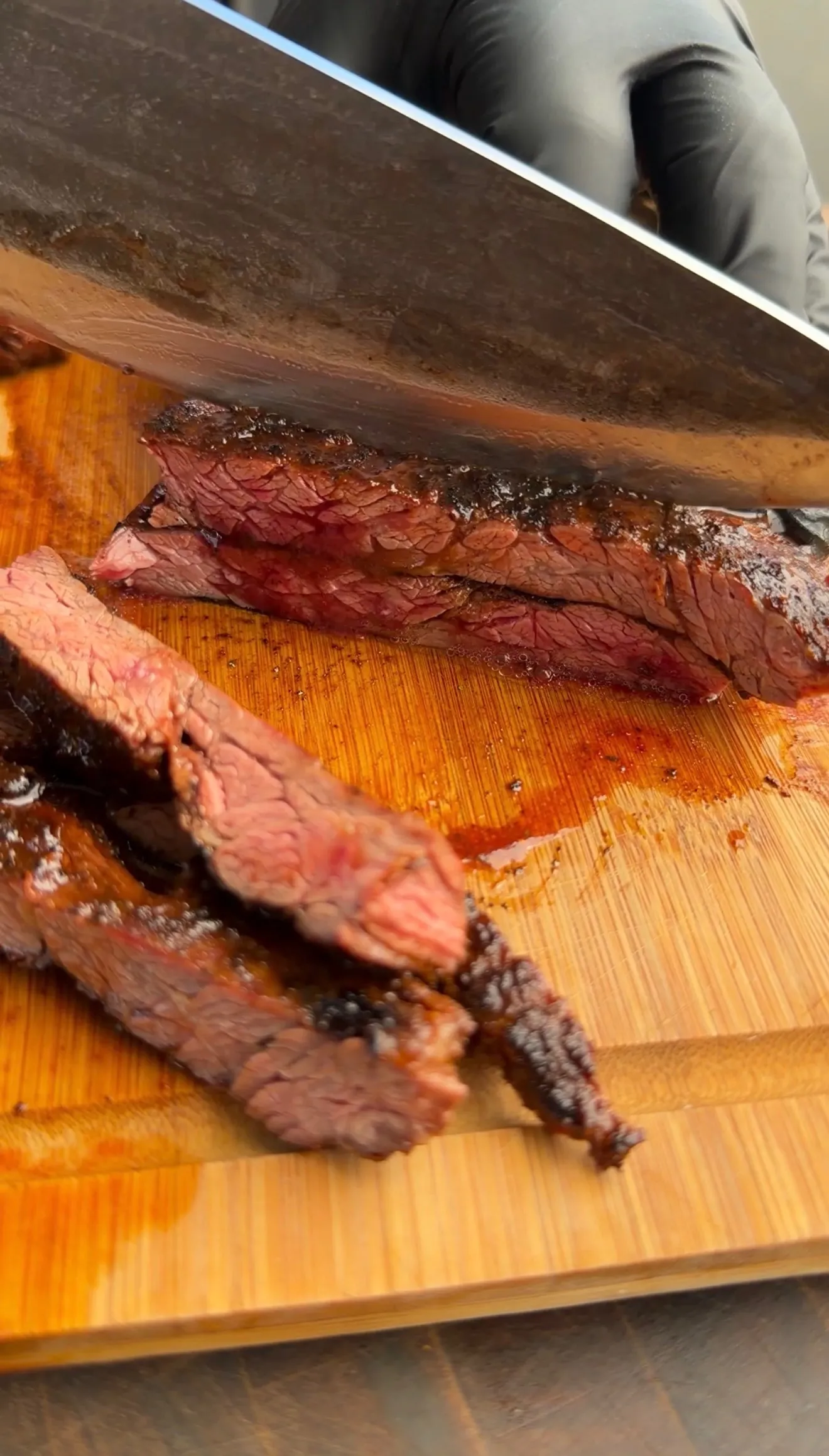 Freshly sliced medium-rare skirt steak on wooden cutting board with knife for tacos