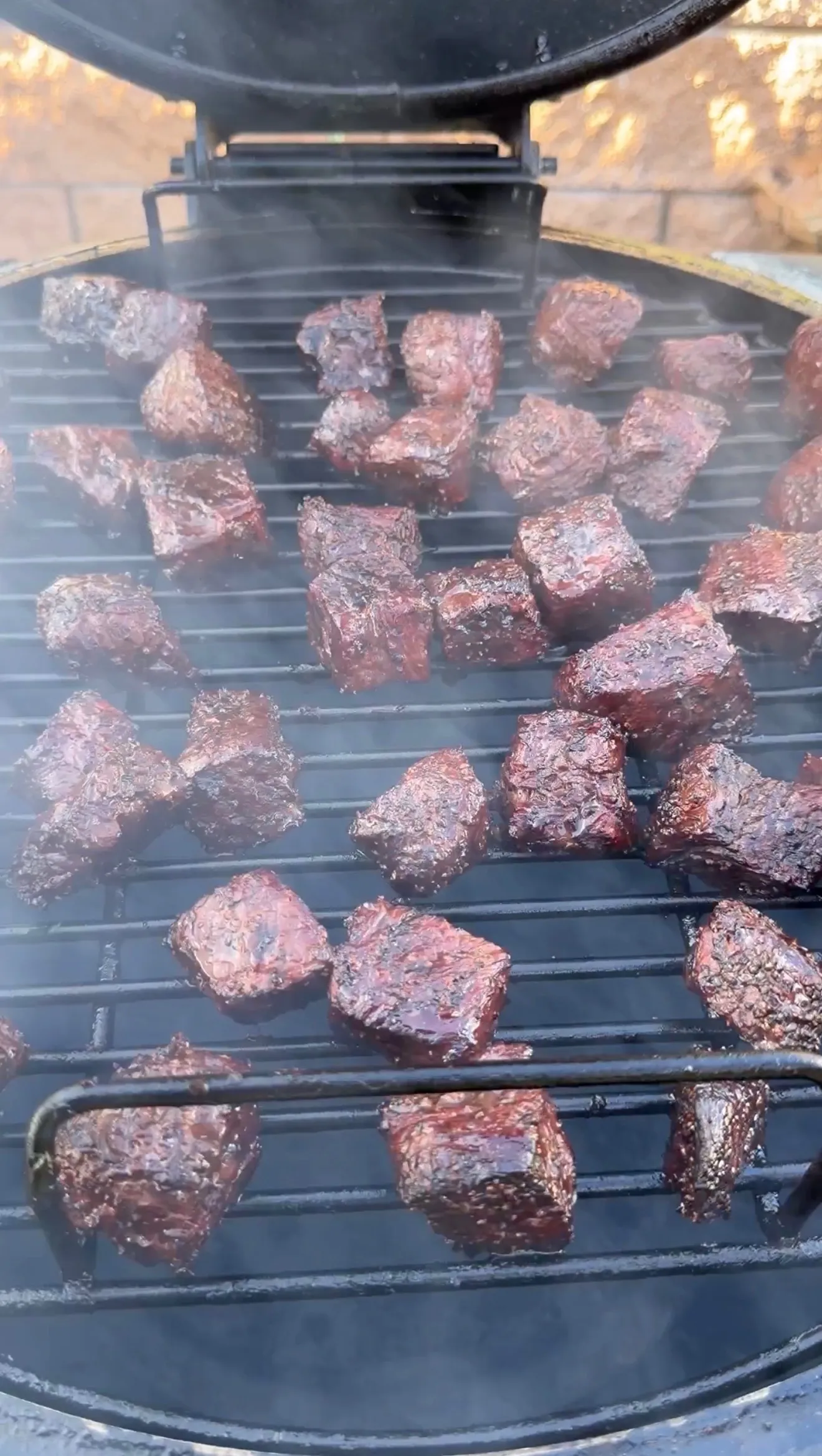 Smoked molasses coffee beef rib burnt ends with dark caramelized crust cooking on round grill grates