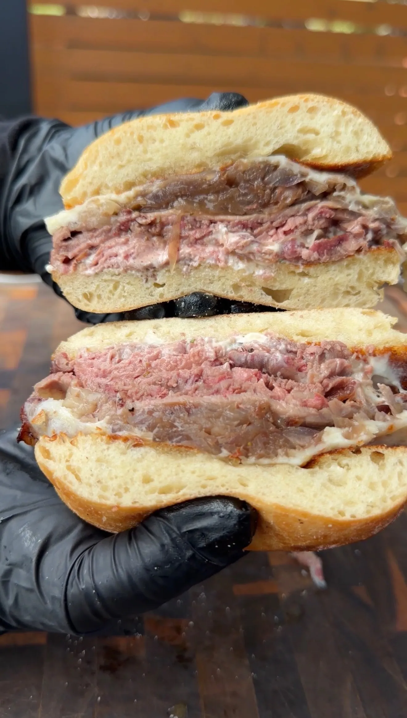 Cross-section of garlic herb butter smoked prime rib French dip sandwich showing tender meat layers on crusty bread