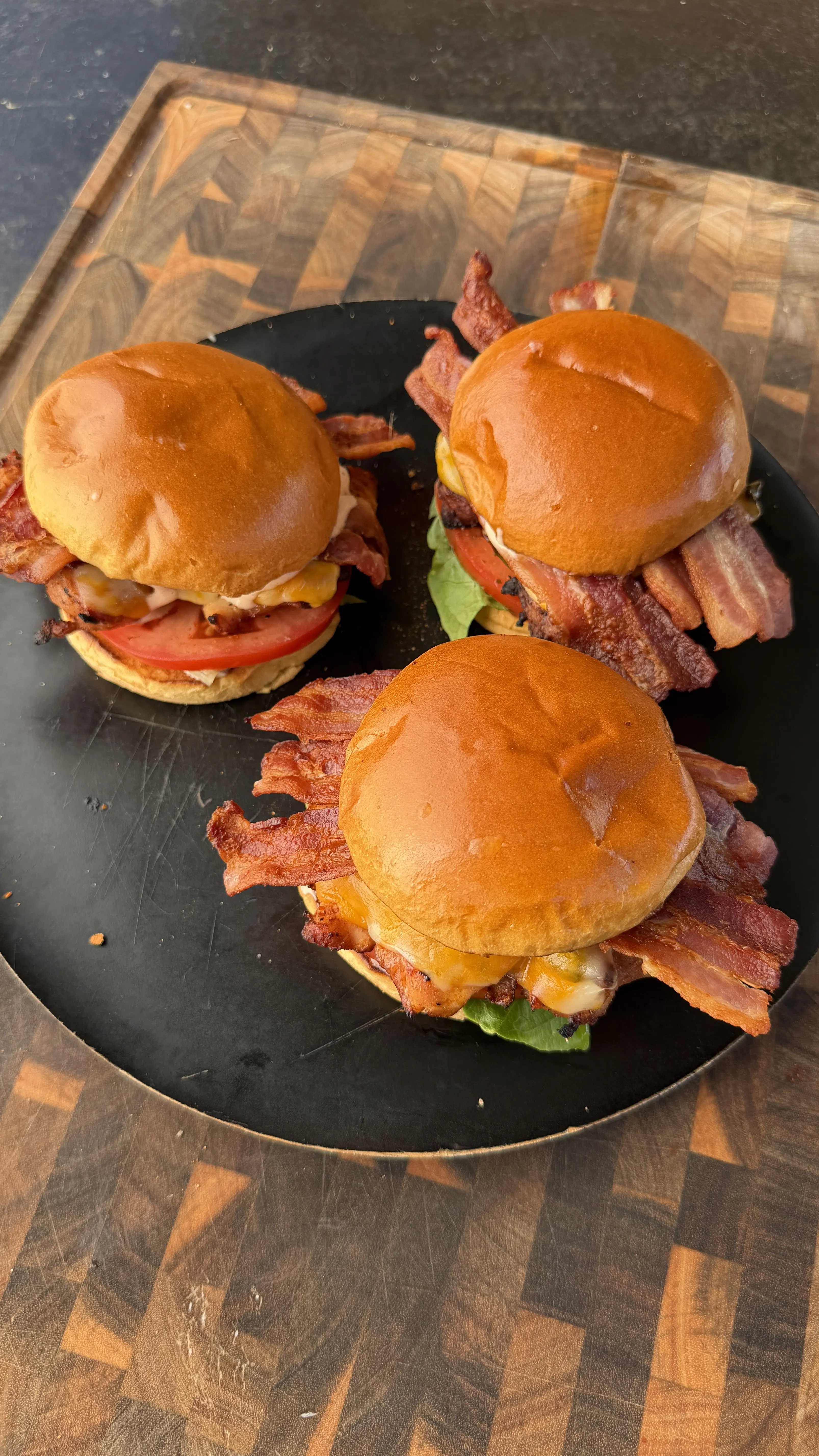 Three spicy chicken BLT sandwiches with crispy bacon, lettuce, tomato, and cheese on brioche buns