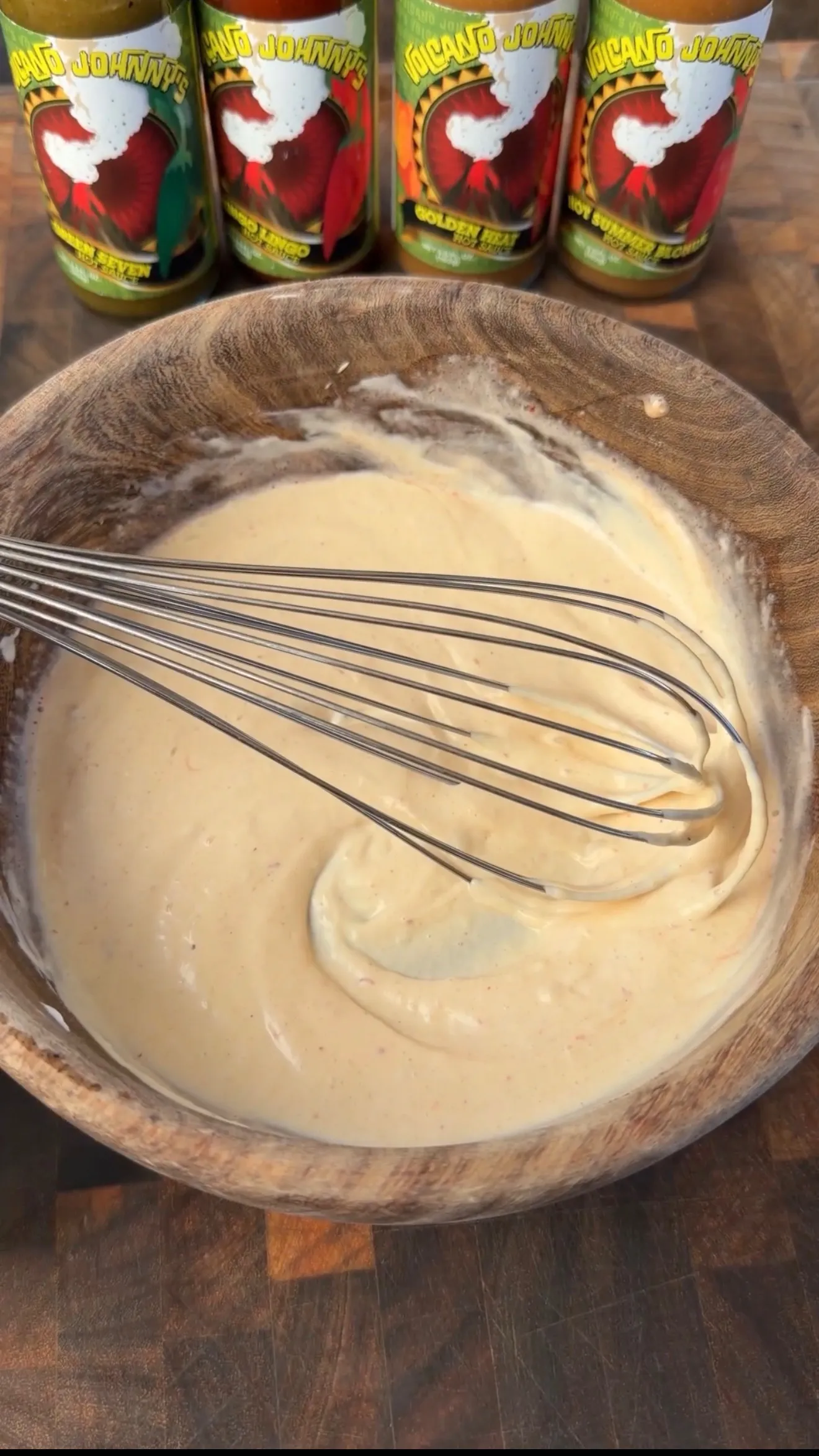 Creamy spicy aioli being whisked smooth in a wooden bowl