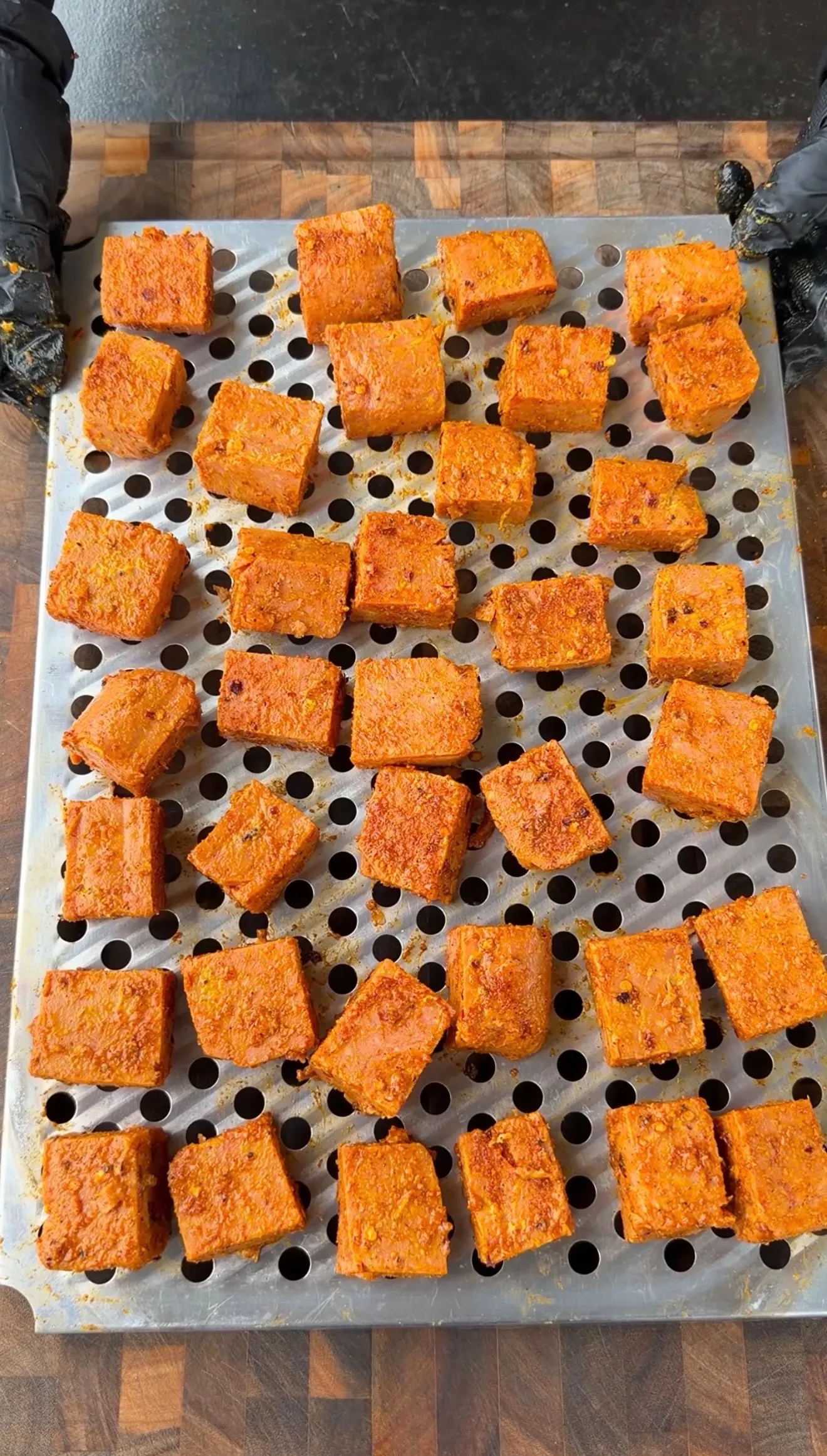 Seasoned spam burnt ends coated in orange spice rub arranged on a perforated metal air fryer tray