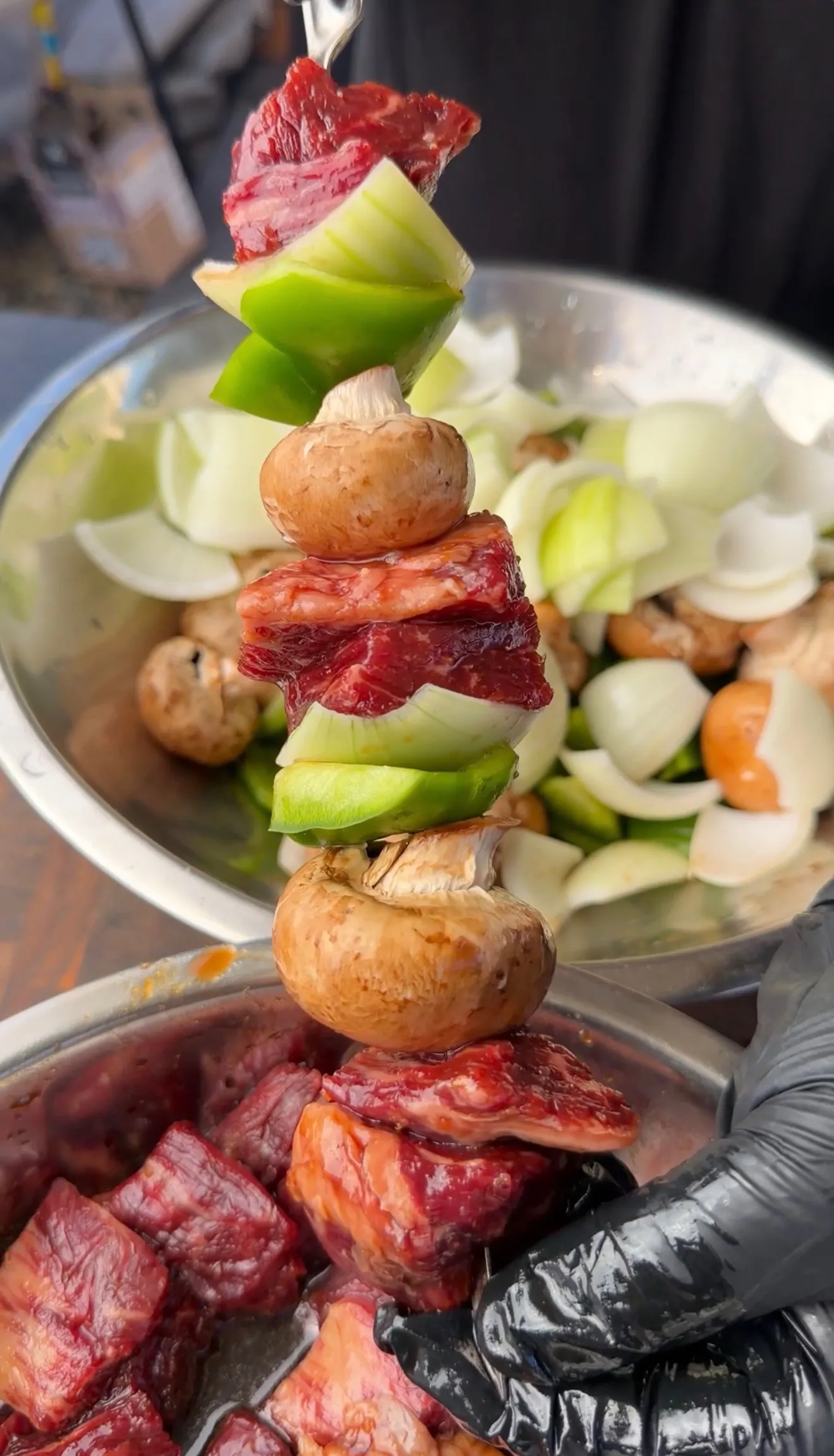 Teriyaki beef skewers with mushrooms and bell peppers being prepared over a pot of mixed vegetables