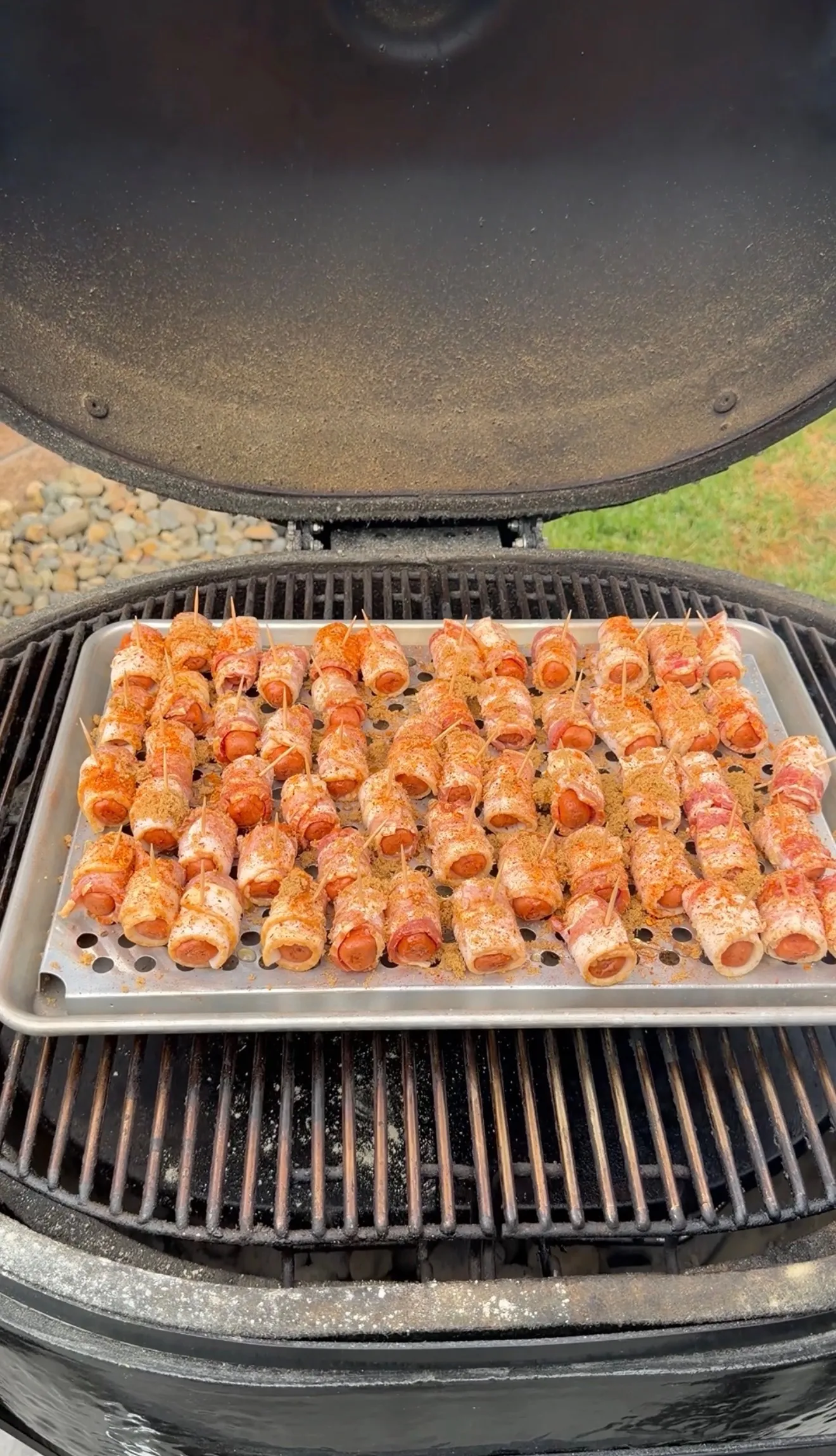 Cajun honey bacon-wrapped little smokies dusted with brown sugar and spices on a smoker grill rack