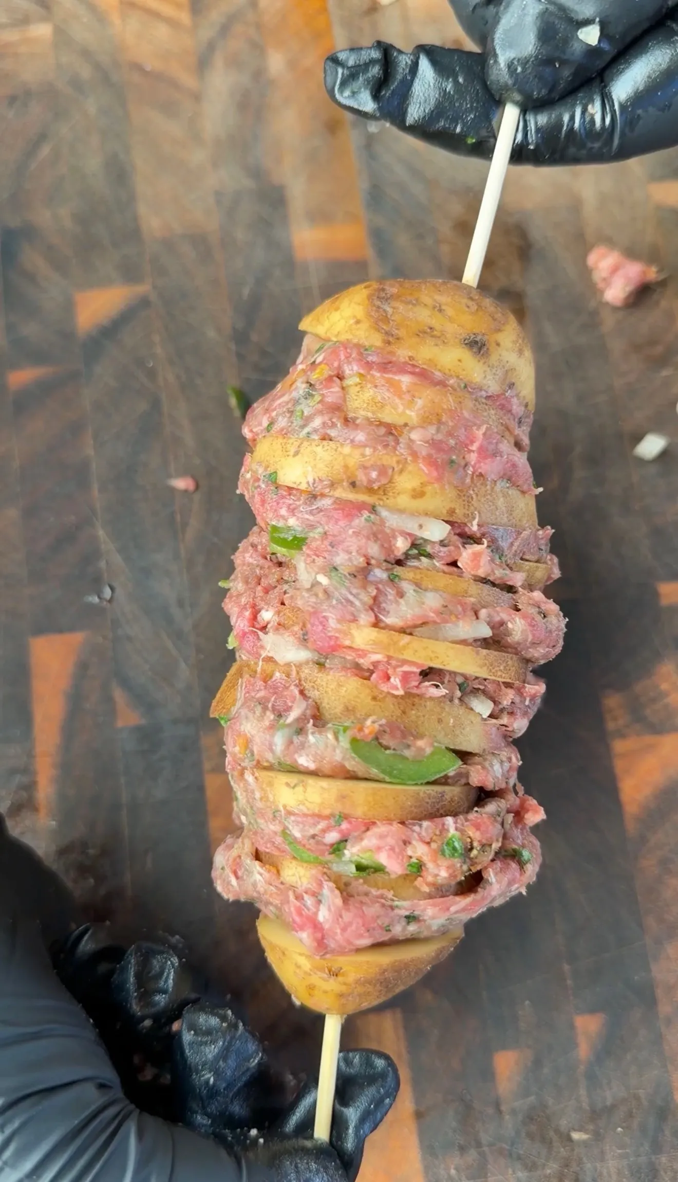 Raw Cajun butter beef and potato kebab on a skewer, layered with seasoned ground beef, peppers, and onions