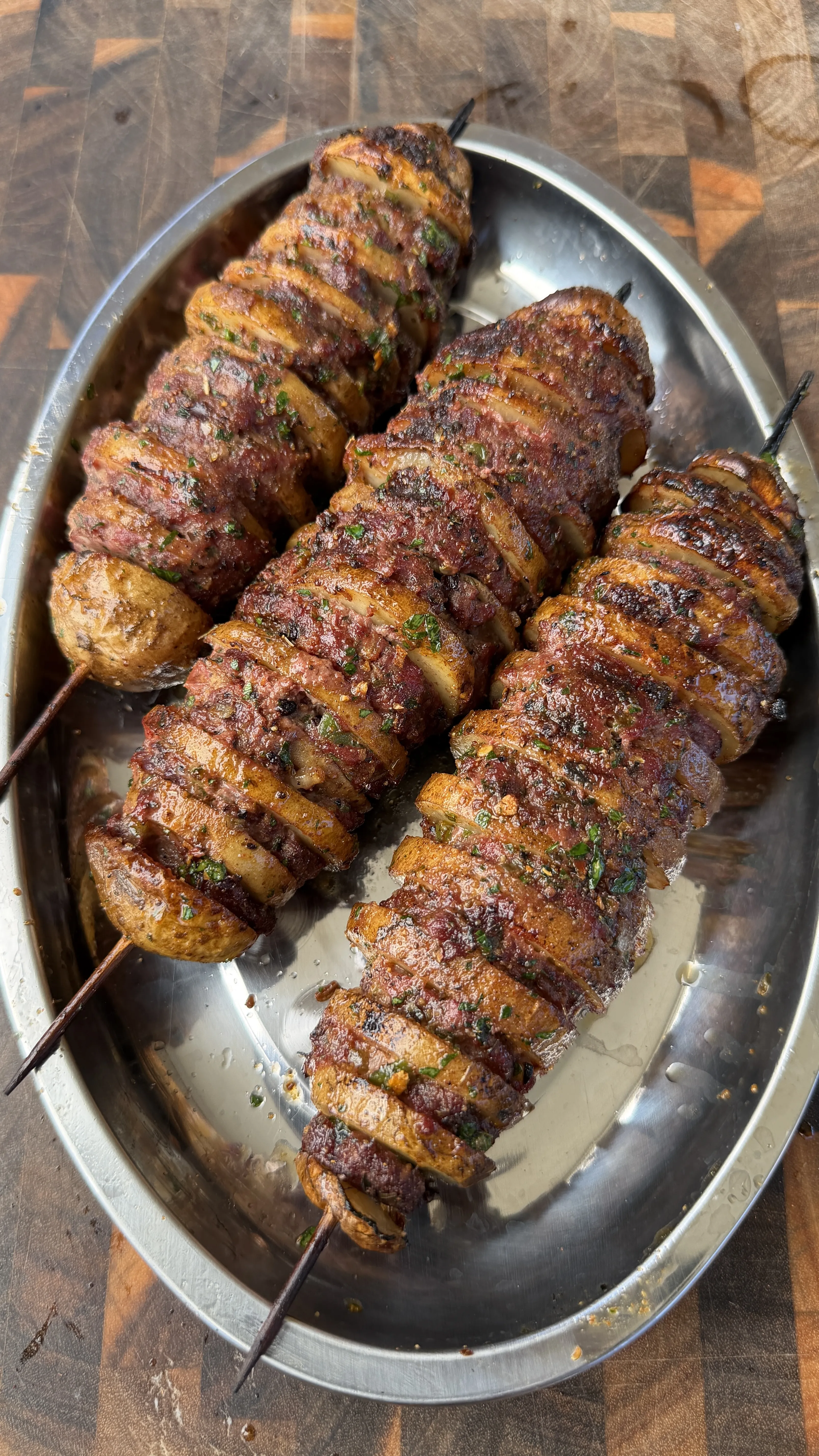 Cajun butter potato beef kebabs on a silver oval platter, skewered and seasoned with herbs and spices