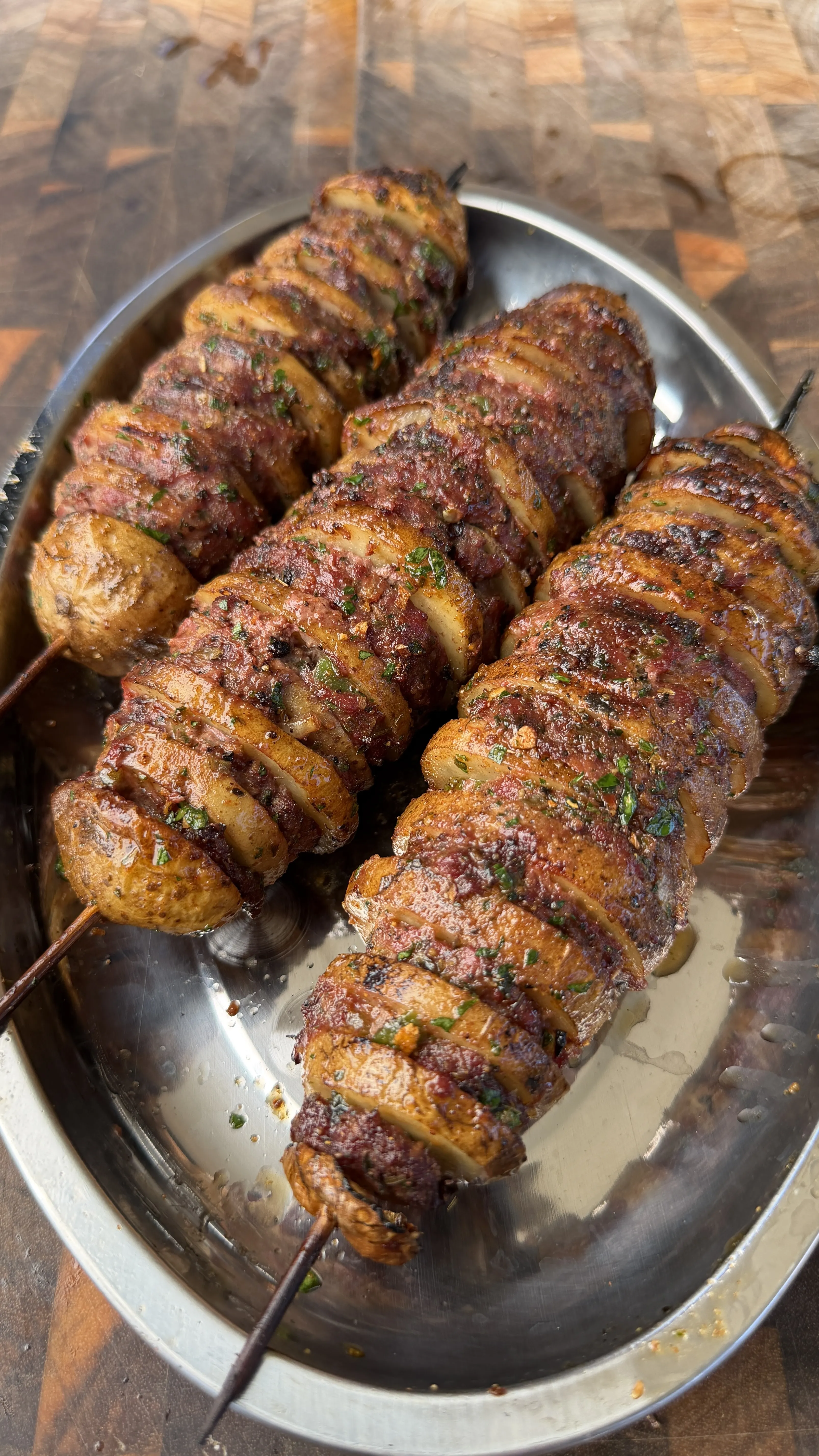 Three Cajun butter potato beef kebabs on metal skewers, seasoned with herbs and spices, served on a silver platter