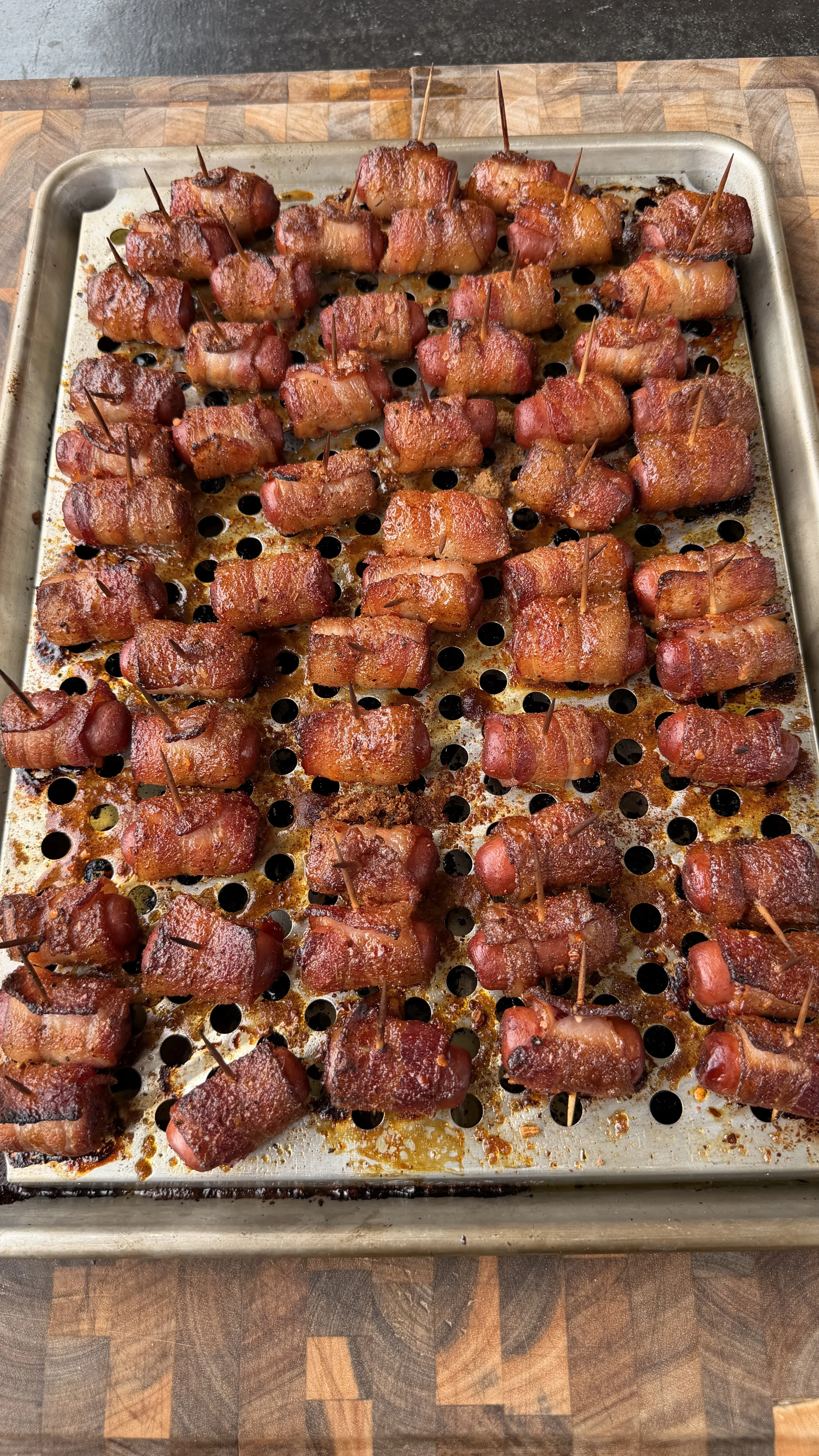 Cajun honey bacon-wrapped little smokies secured with toothpicks on a perforated baking sheet, caramelized and golden brown