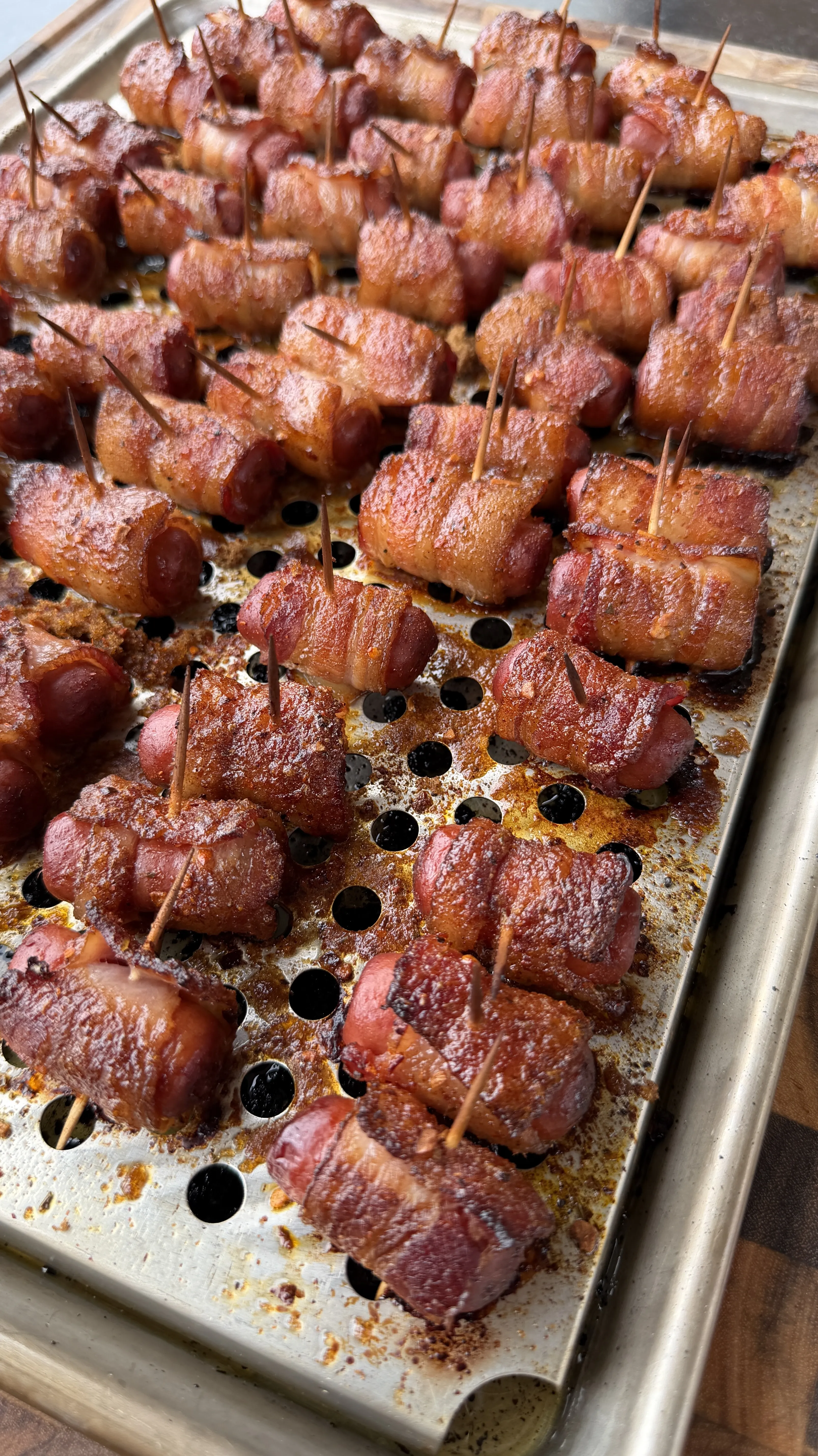 Cajun honey bacon-wrapped little smokies secured with toothpicks, caramelized and golden on a perforated baking sheet