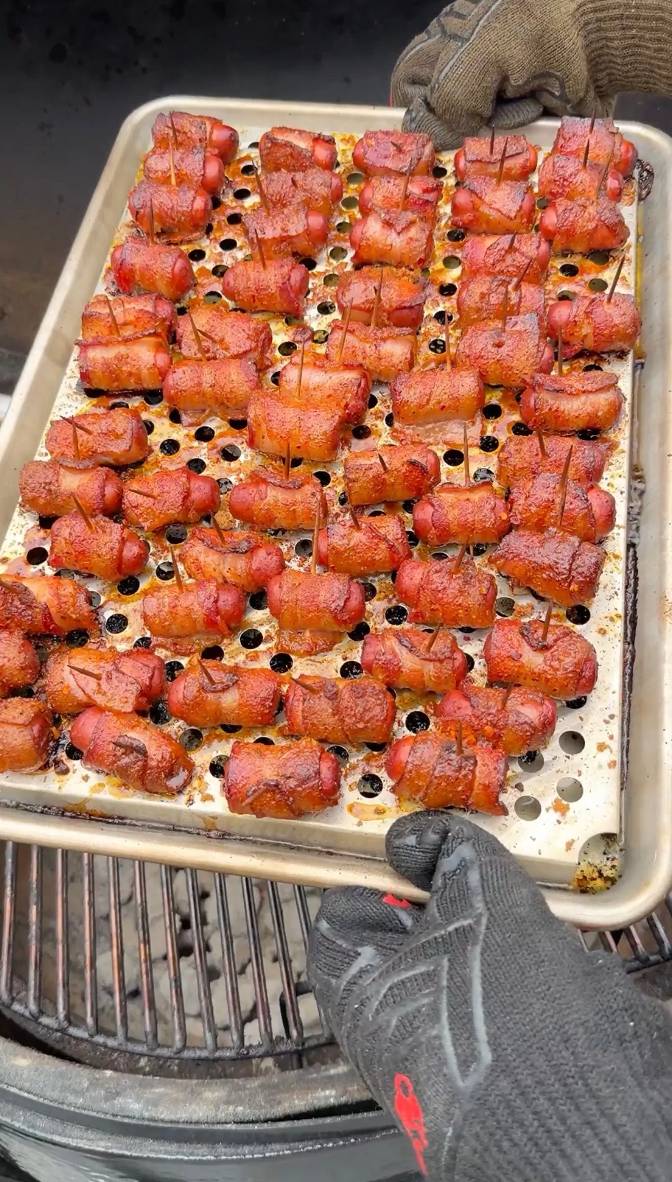 Smoky bacon-wrapped little smokies with toothpicks on a perforated grill tray, glazed with Cajun honey seasoning