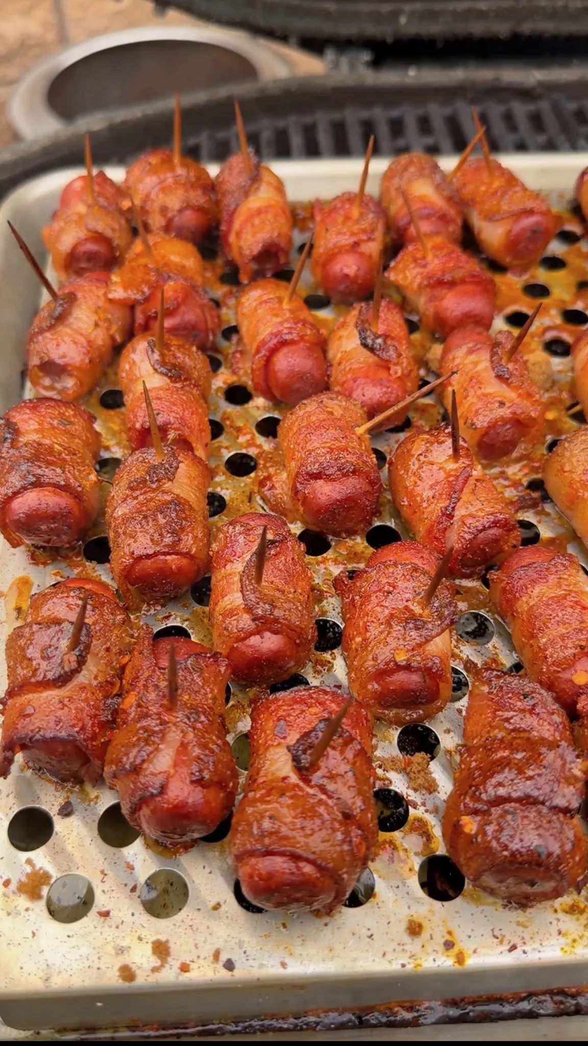 Cajun honey bacon-wrapped little smokies secured with toothpicks, caramelized and golden on a perforated grill tray