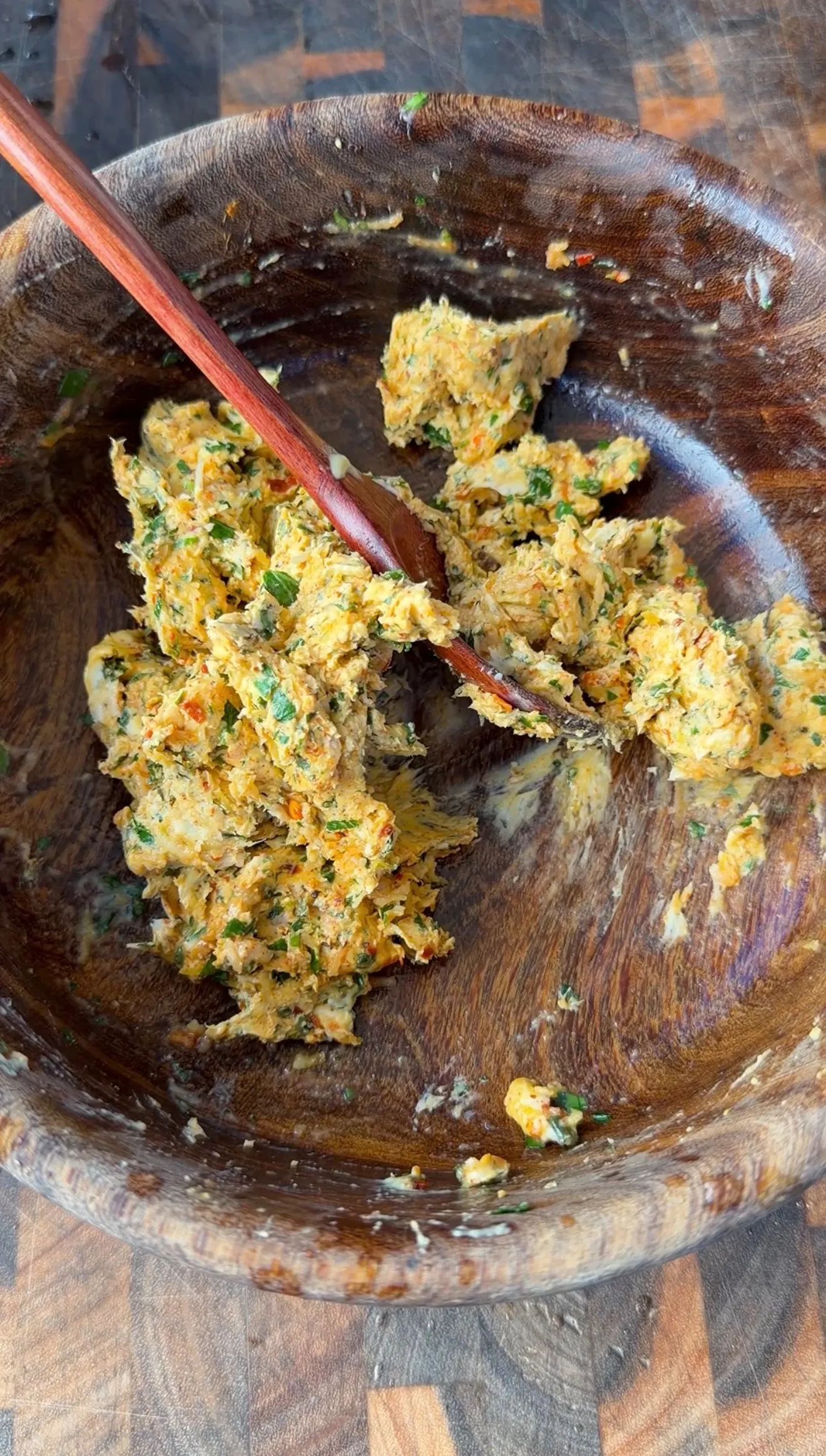 Herbed cowboy butter mixture with fresh herbs and spices stirred together in a rustic wooden bowl