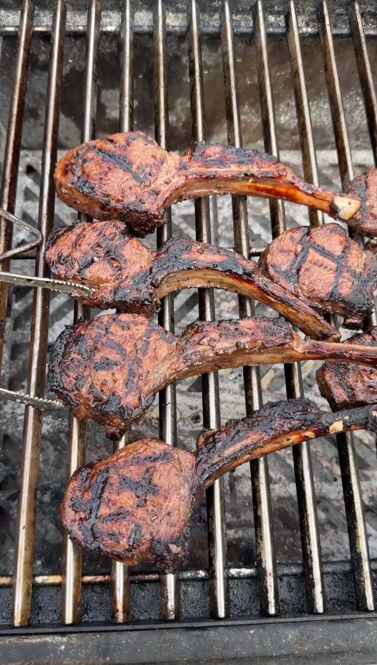 Garlic and sherry marinated lamb lollipops with char grill marks cooking on a charcoal grill