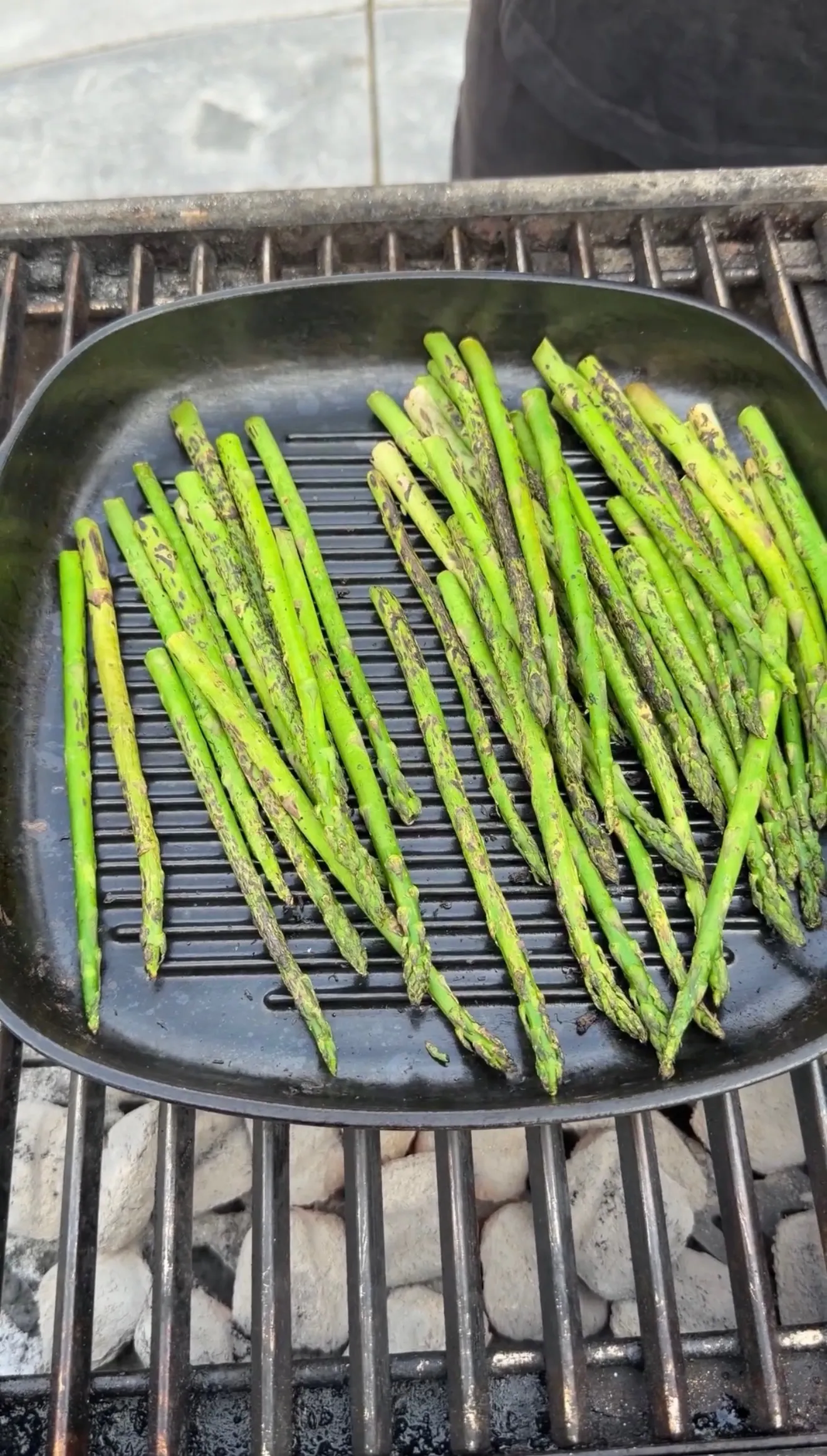 Fresh asparagus spears grilling on a cast iron ridged pan over charcoal, served alongside garlic sherry lamb lollipops