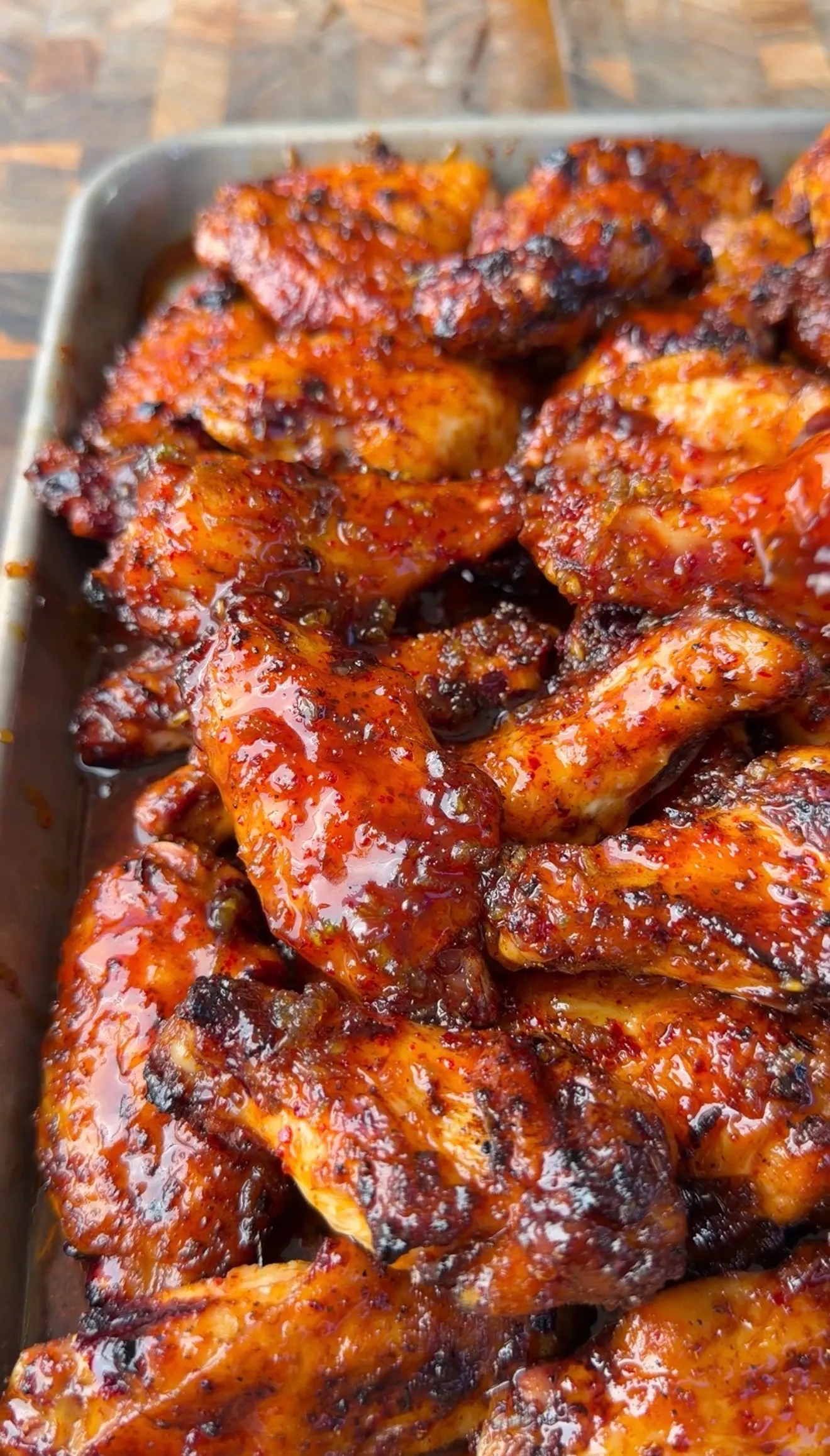 Sticky honey garlic chicken wings with caramelized glaze piled on a metal baking sheet