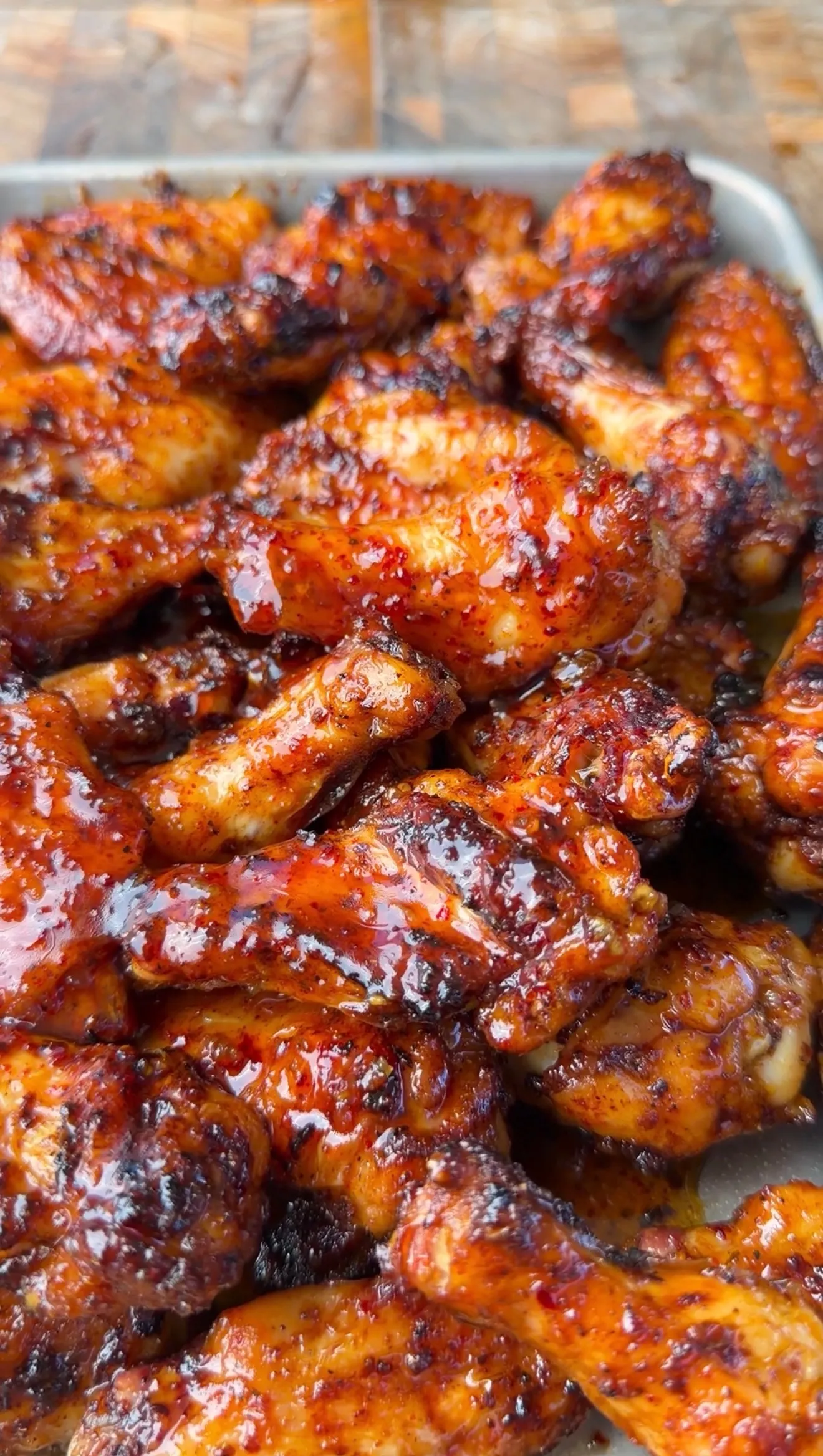 Sticky honey garlic chicken wings with caramelized glaze piled on a metal baking tray