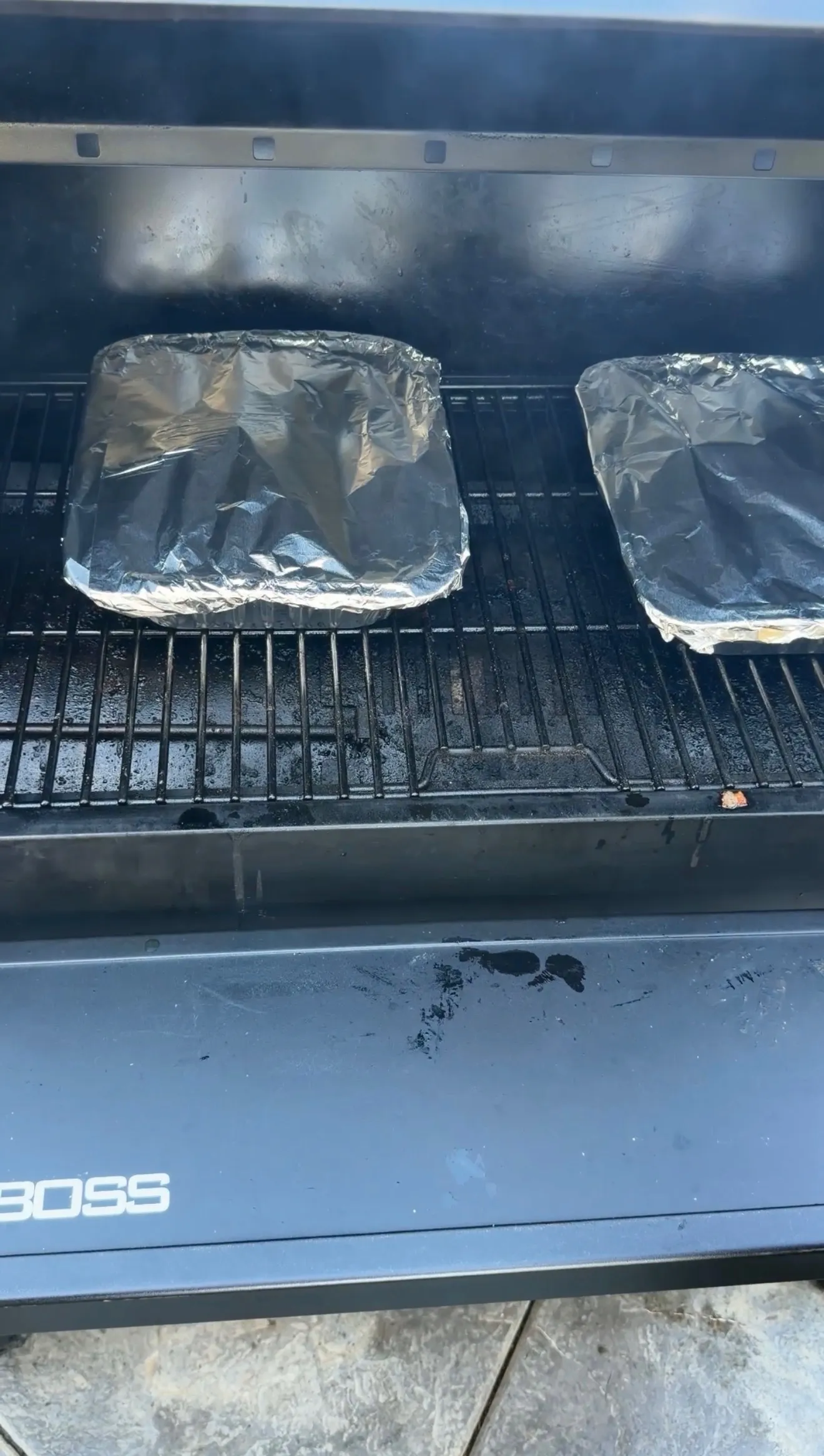 Brown sugar bourbon party ribs wrapped in aluminum foil pans smoking on a Pit Boss pellet grill