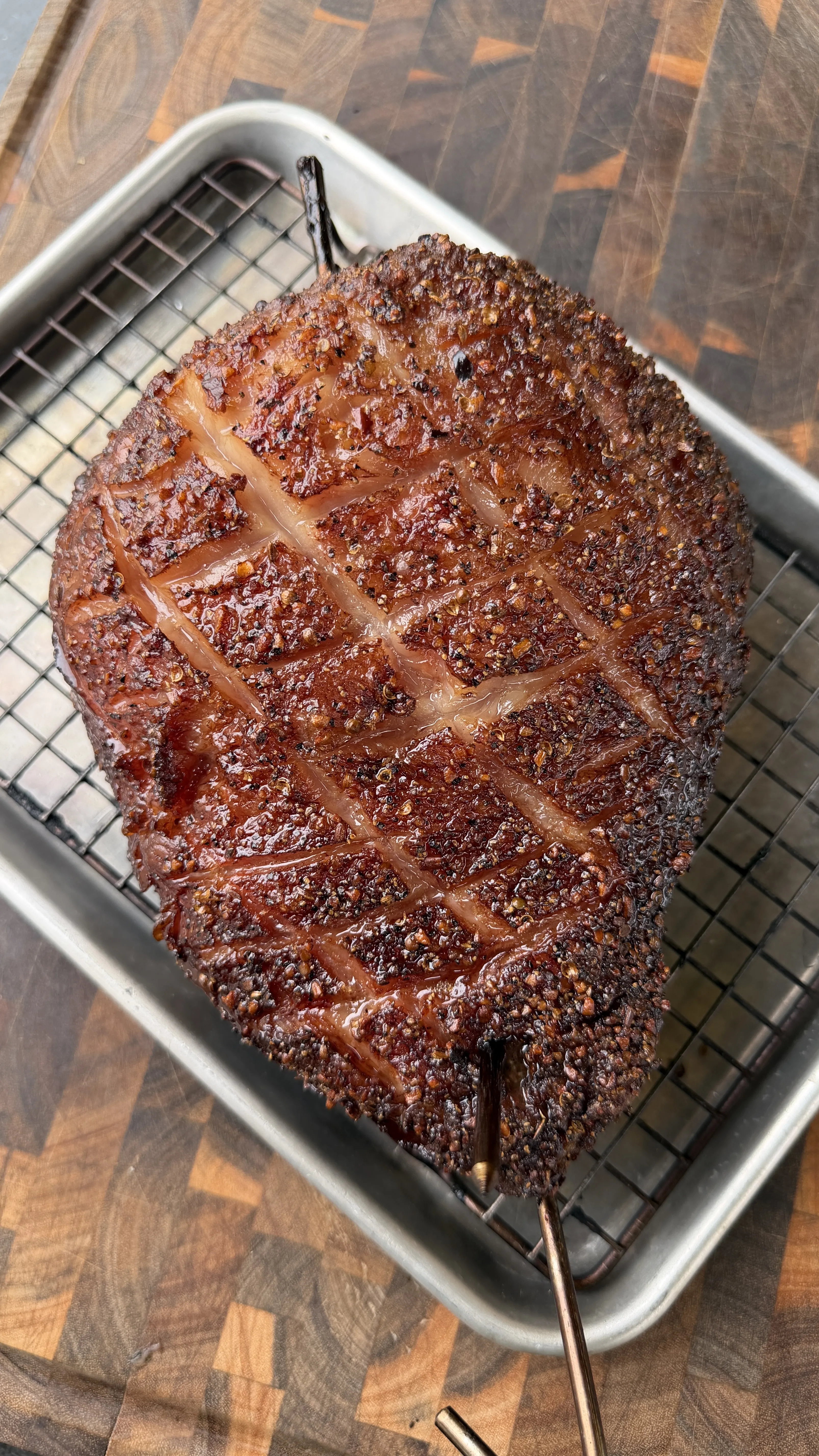 Smoked picanha roast with scored fat cap crust on a wire rack in a roasting pan