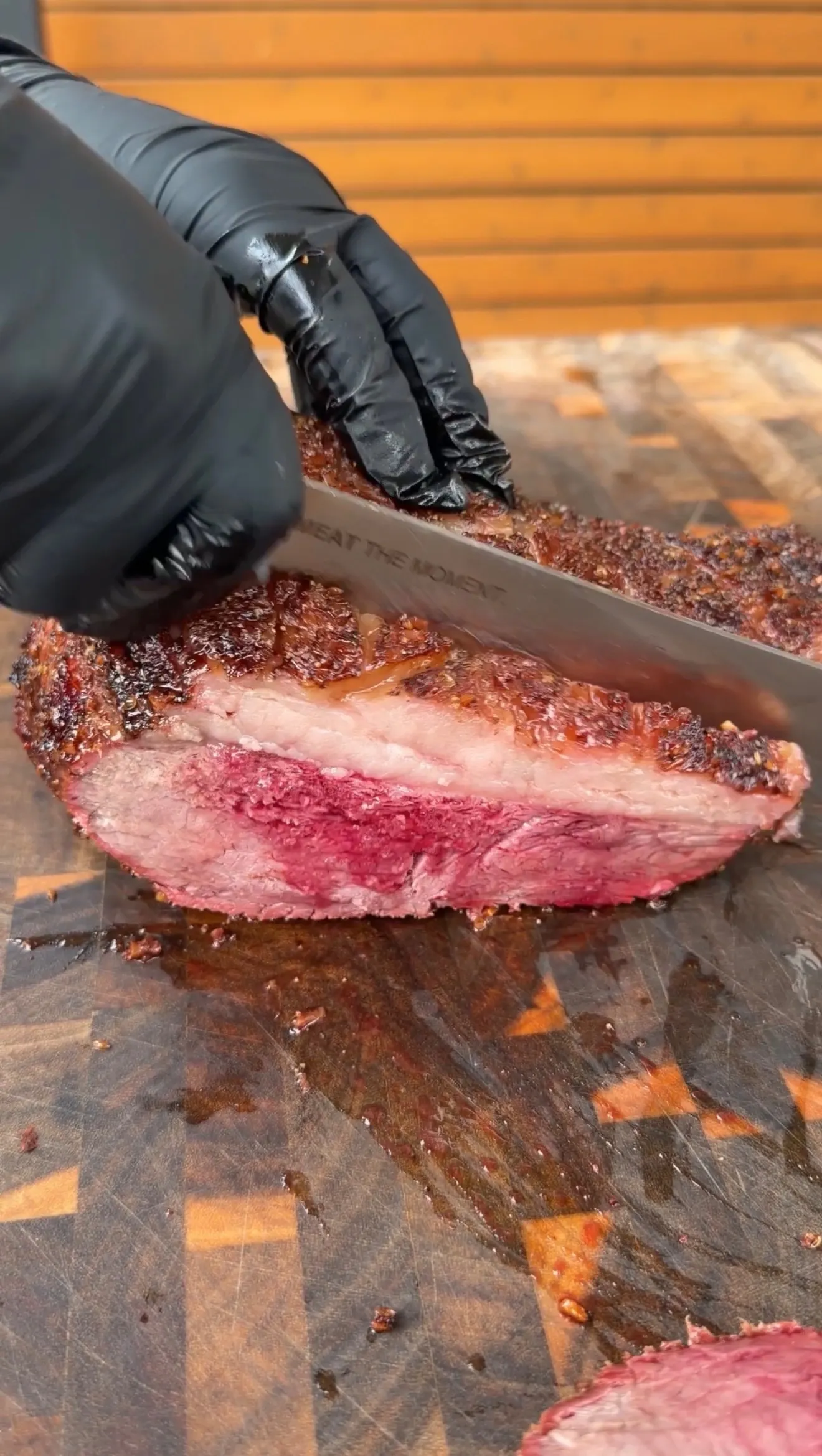Sliced smoked picanha roast with dark crust and pink smoke ring on a wooden cutting board