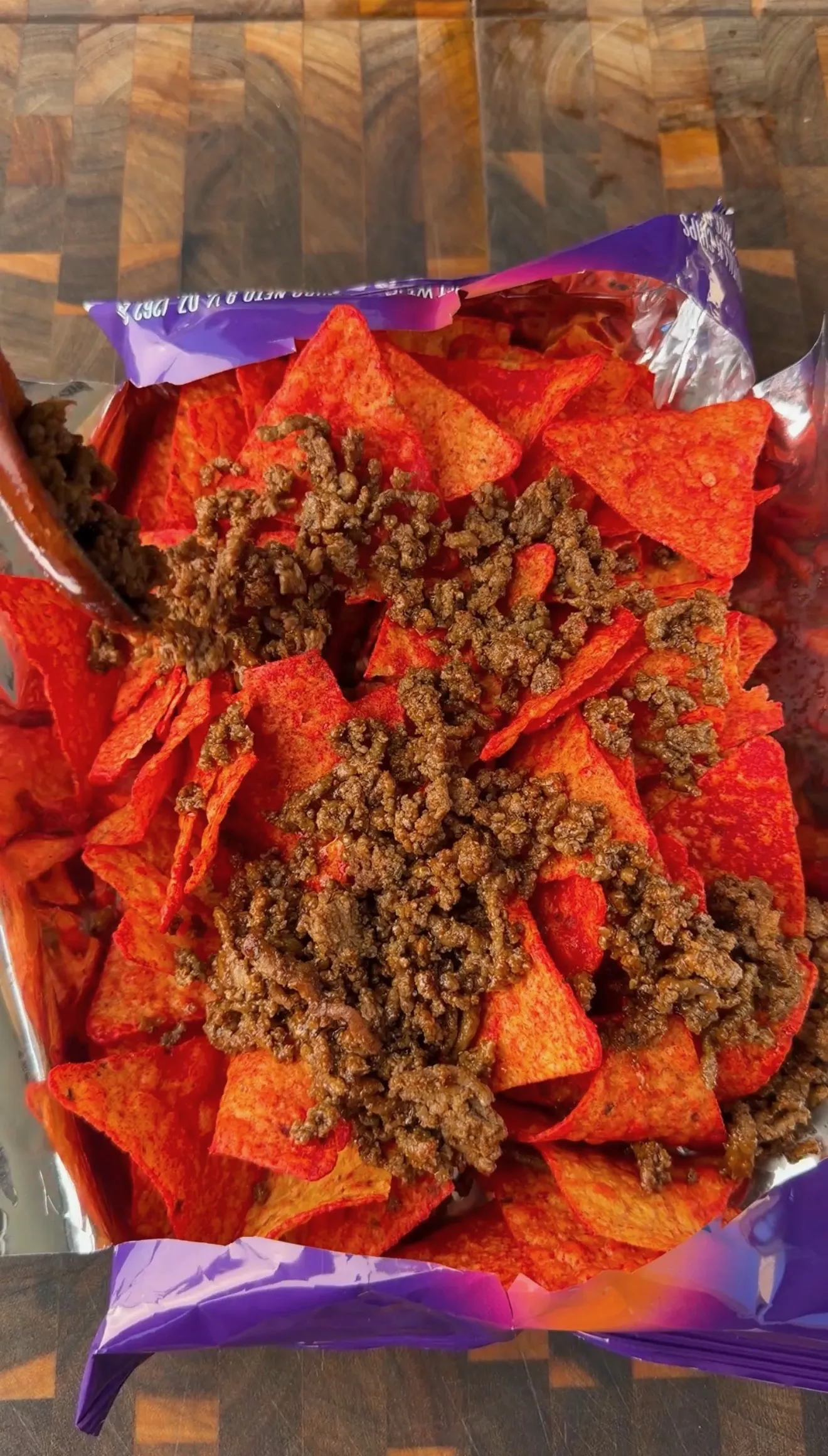 Seasoned taco meat piled on top of red Doritos chips inside an open chip bag for walking tacos