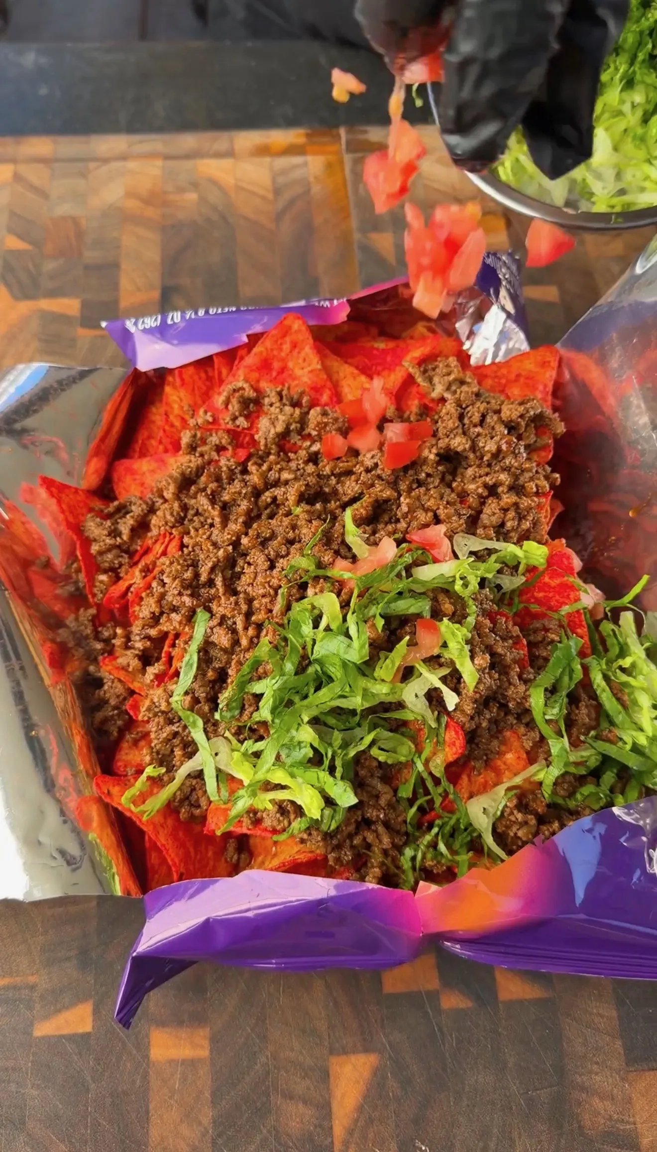 Walking tacos served in an open Doritos bag topped with seasoned ground beef, shredded lettuce, and diced tomatoes