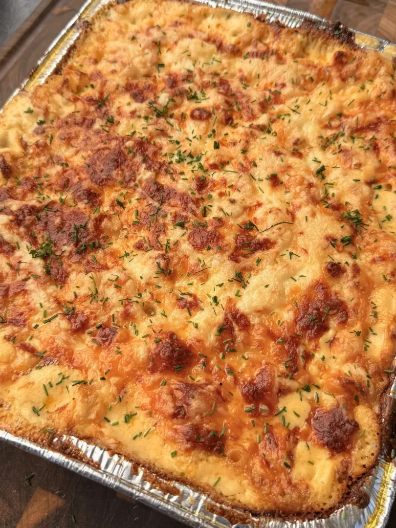 Creamy baked mac and cheese with golden brown crispy top, elbow macaroni, mozzarella, Colby Jack, cheddar, topped with fresh chives