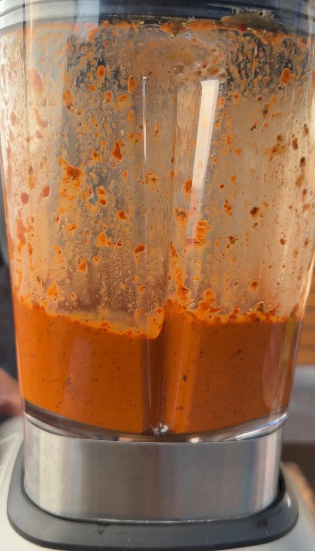 Blended orange-red tomato and pepper sauce inside a blender jar for pork belly porchetta recipe
