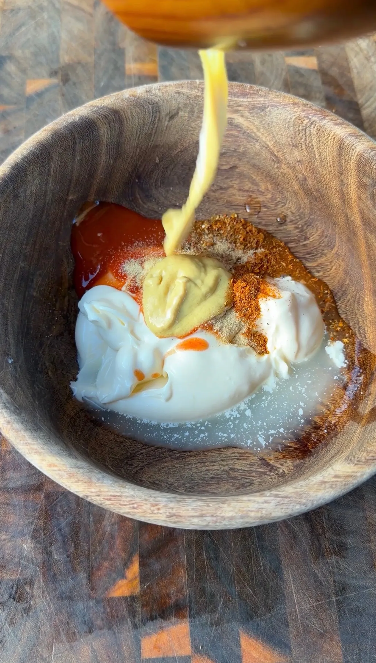 Mayonnaise, mustard, ketchup, and spices in a wooden bowl for smoked fried bologna sandwich sauce