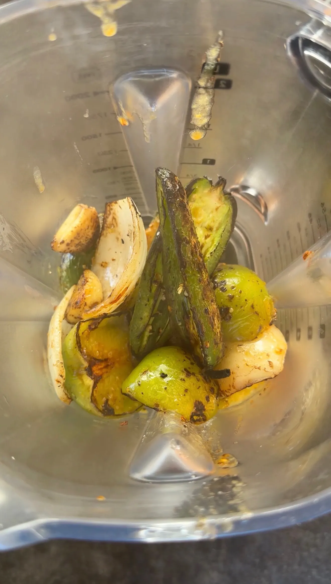 Roasted tomatillos, charred jalapeños, and onion in a blender for chimichanga salsa verde