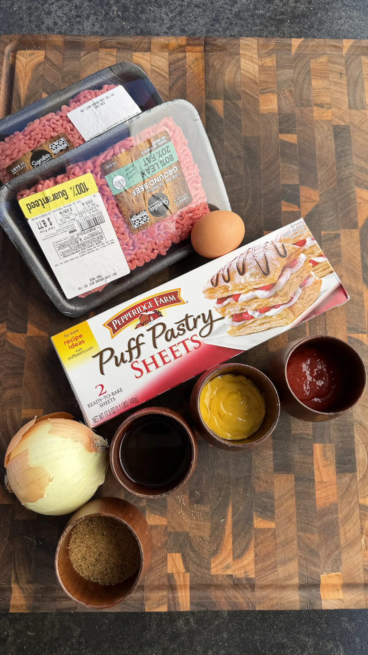 Ingredients for cheeseburger hot pockets: ground beef, puff pastry sheets, egg, onion, mustard, ketchup, and seasonings